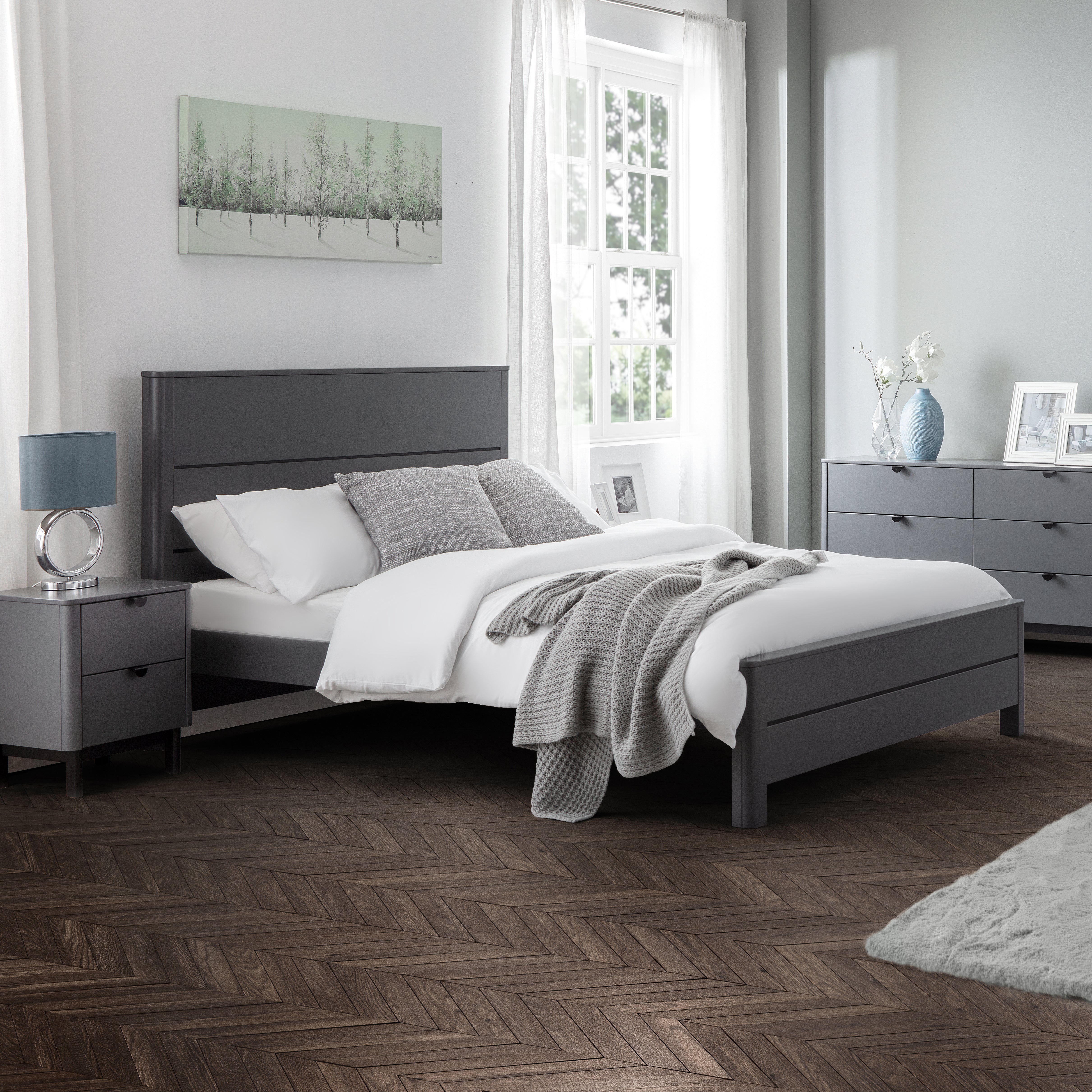 Modern bedroom with gray bed and matching nightstands, white bedding, and decorative elements.