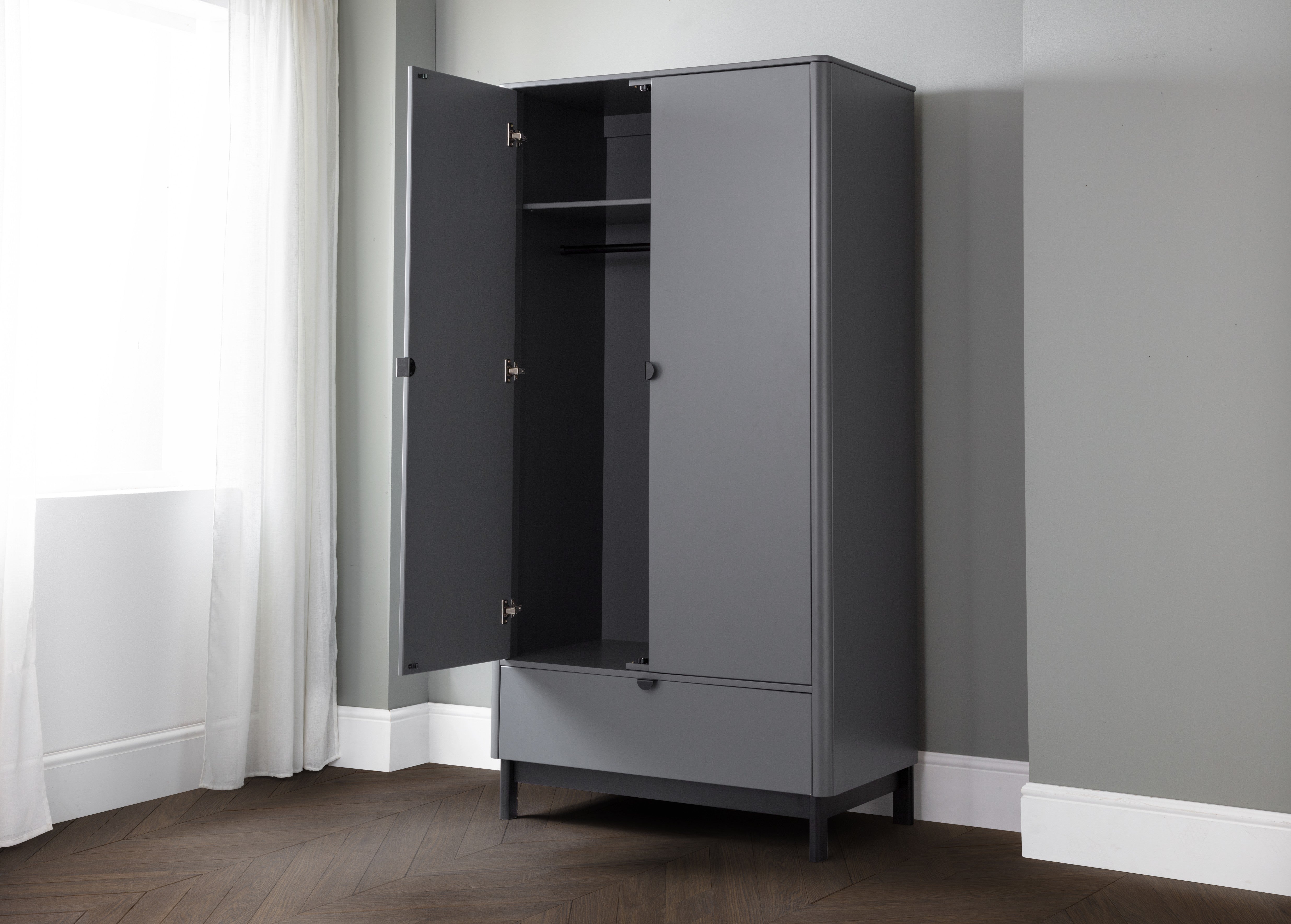 Gray wardrobe with open door in a room with gray walls and white curtains.