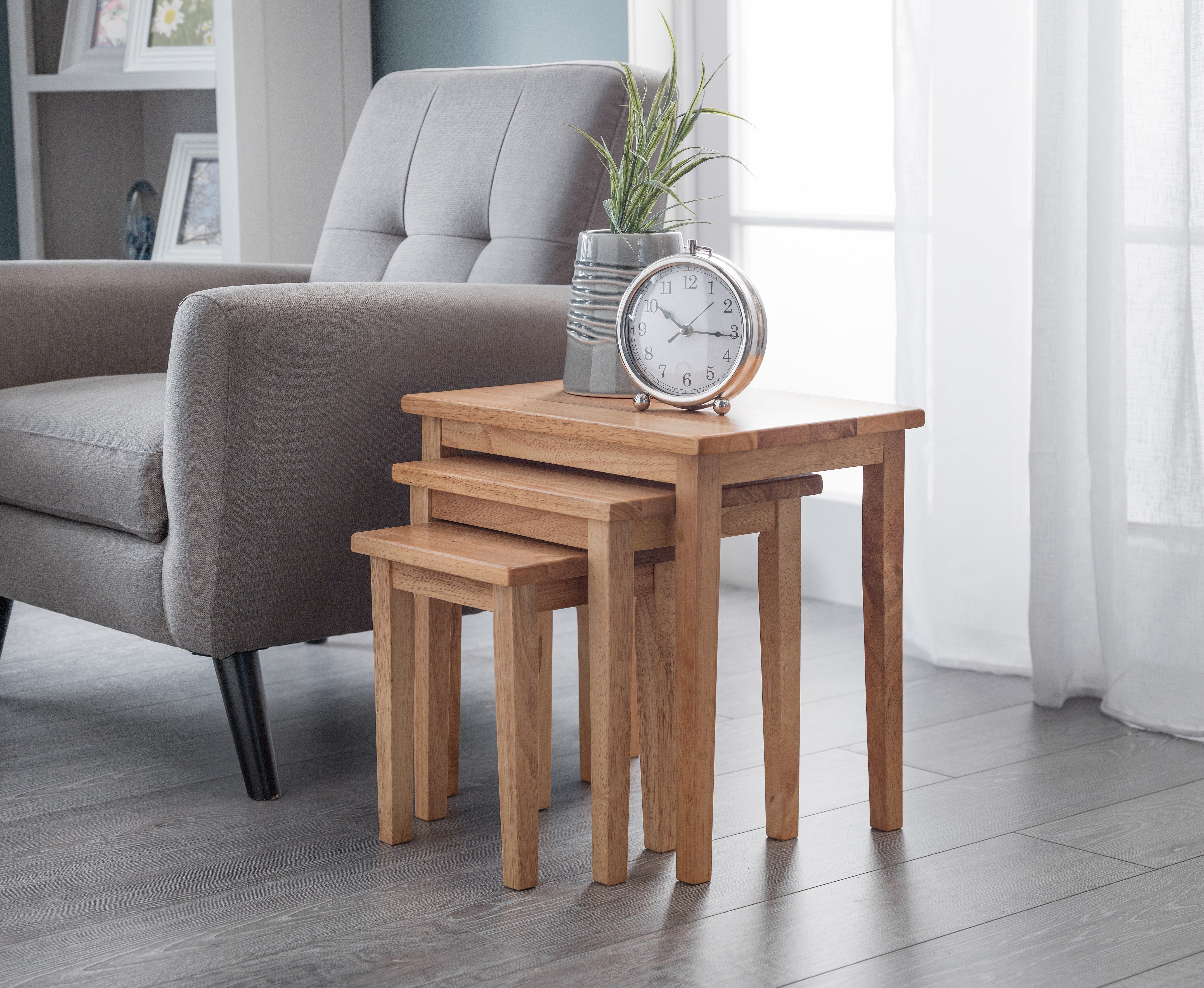 Set of wooden nesting tables with a clock in a living room setting