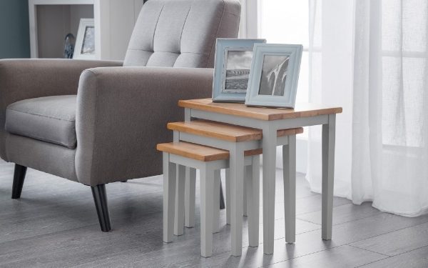 Set of four nesting tables with wooden tops and gray bases in a living room setting.