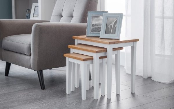 Set of nesting tables with wooden tops and white bases in a living room setting.