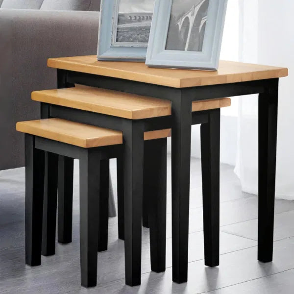 Set of three wooden nesting tables with black legs in a room setting.