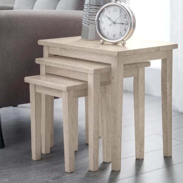 Set of three wooden nesting tables with a clock on top in a room setting.