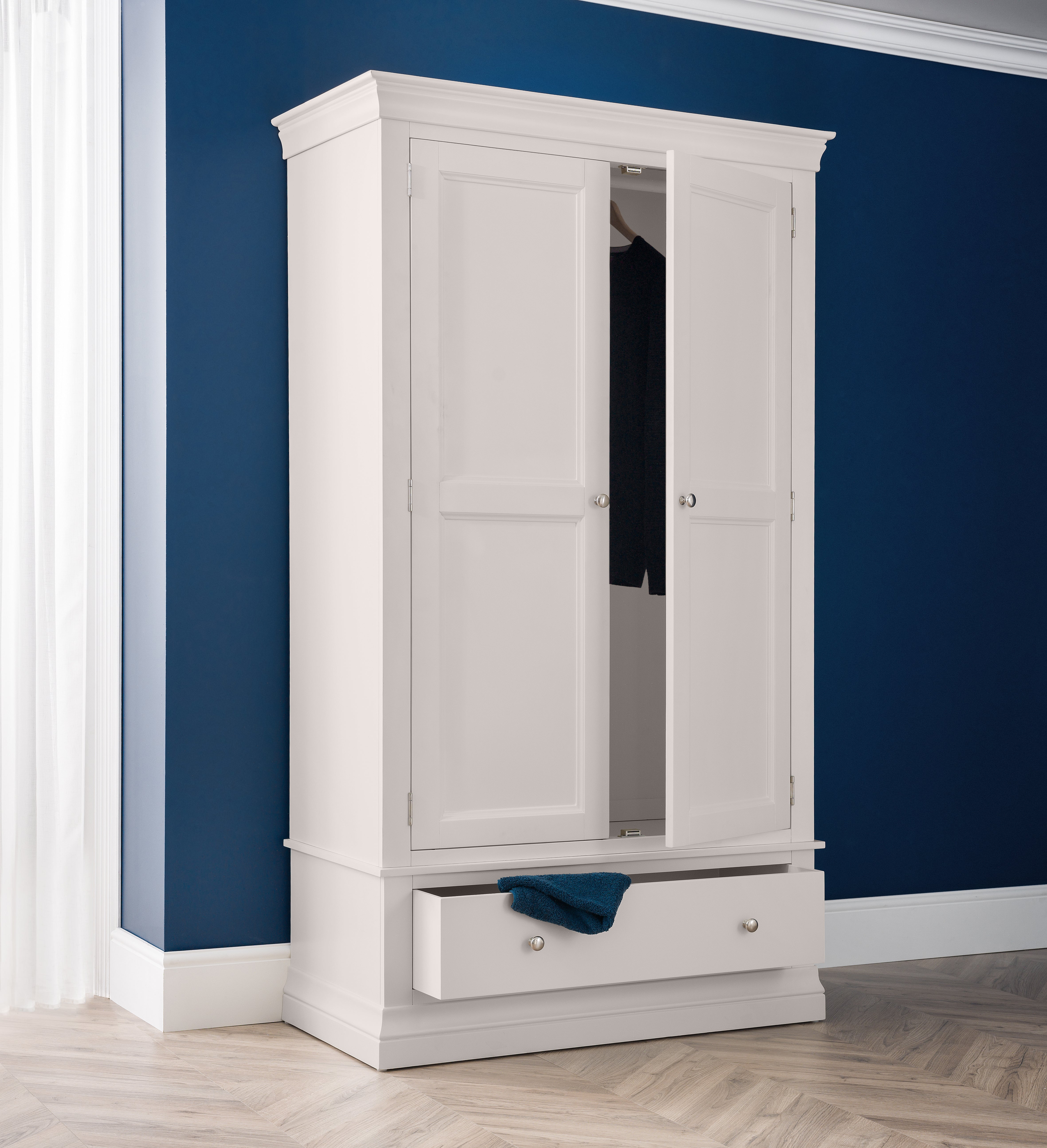 White wardrobe with a mirror against a blue wall