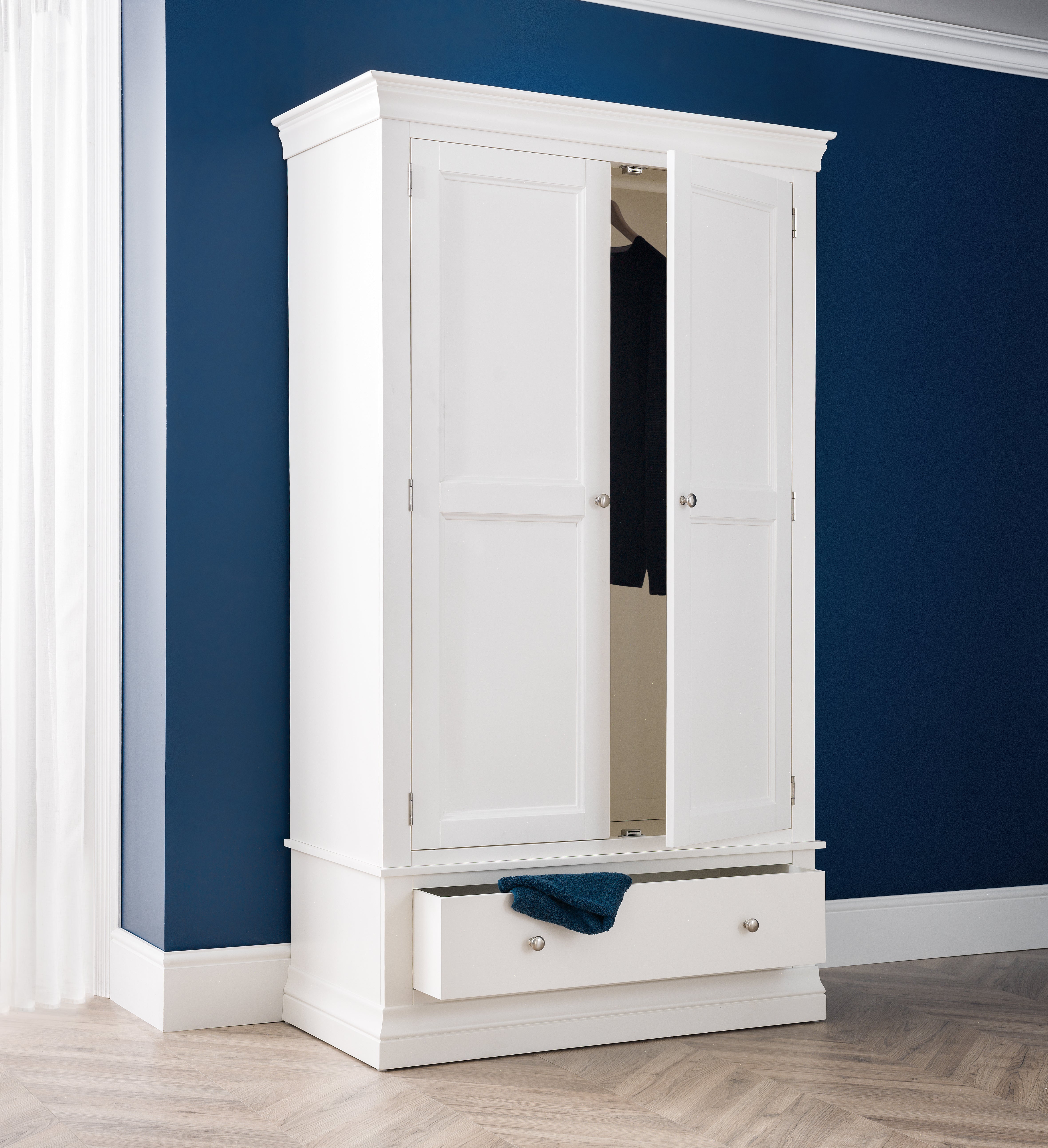 White wardrobe with a mirror against a blue wall
