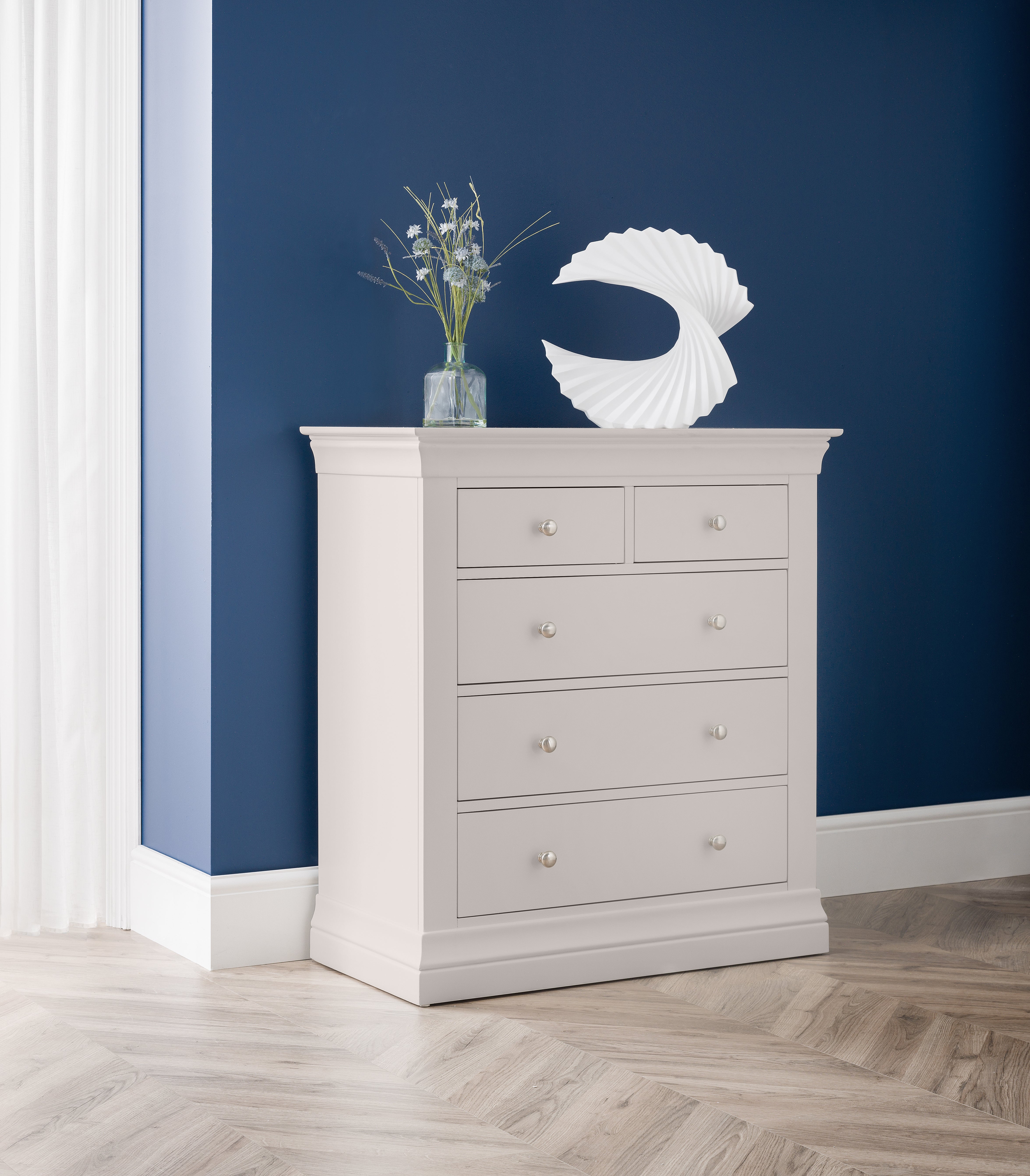 White dresser with decorative items against a blue wall