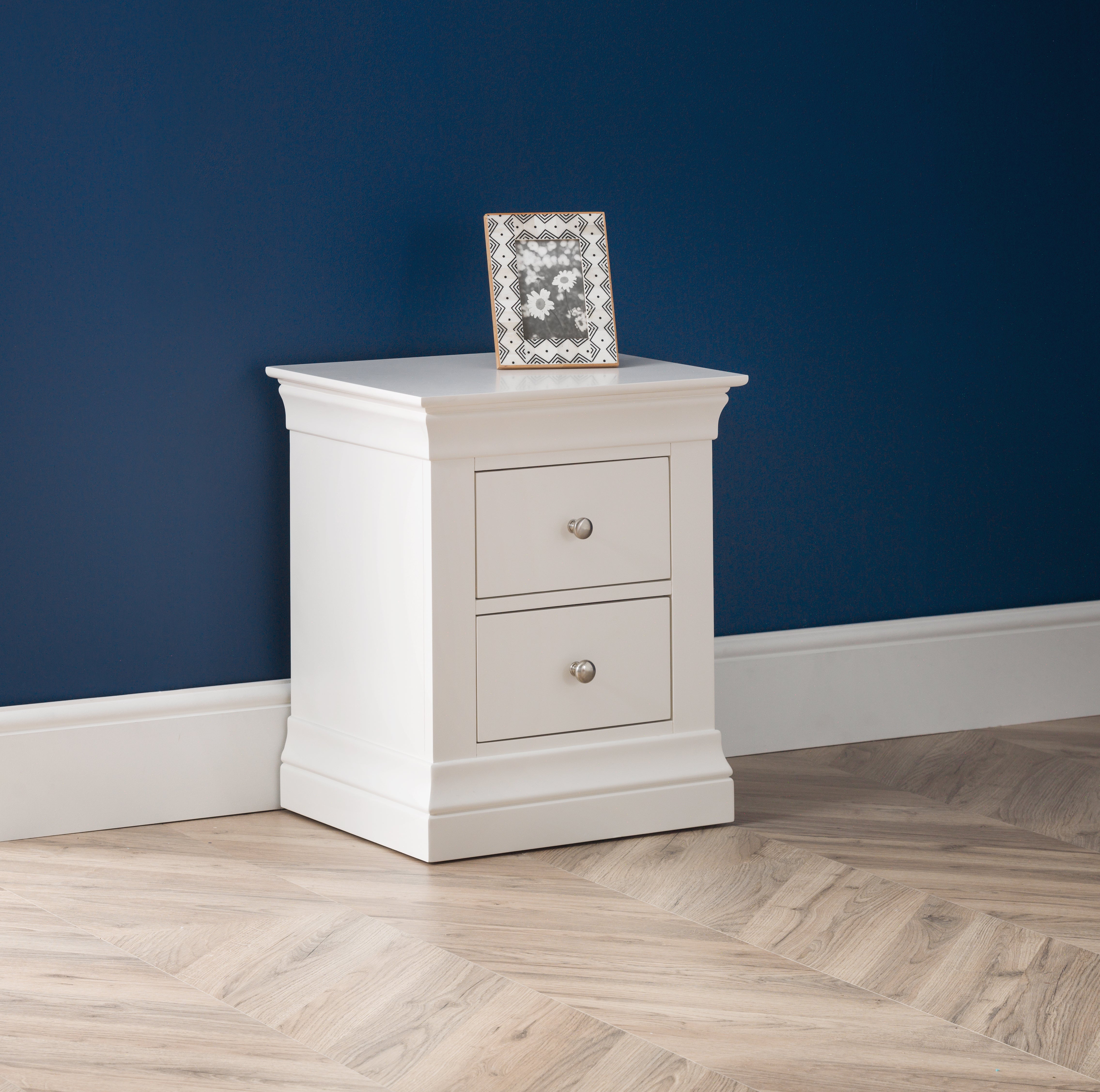 White nightstand with two drawers against a blue wall