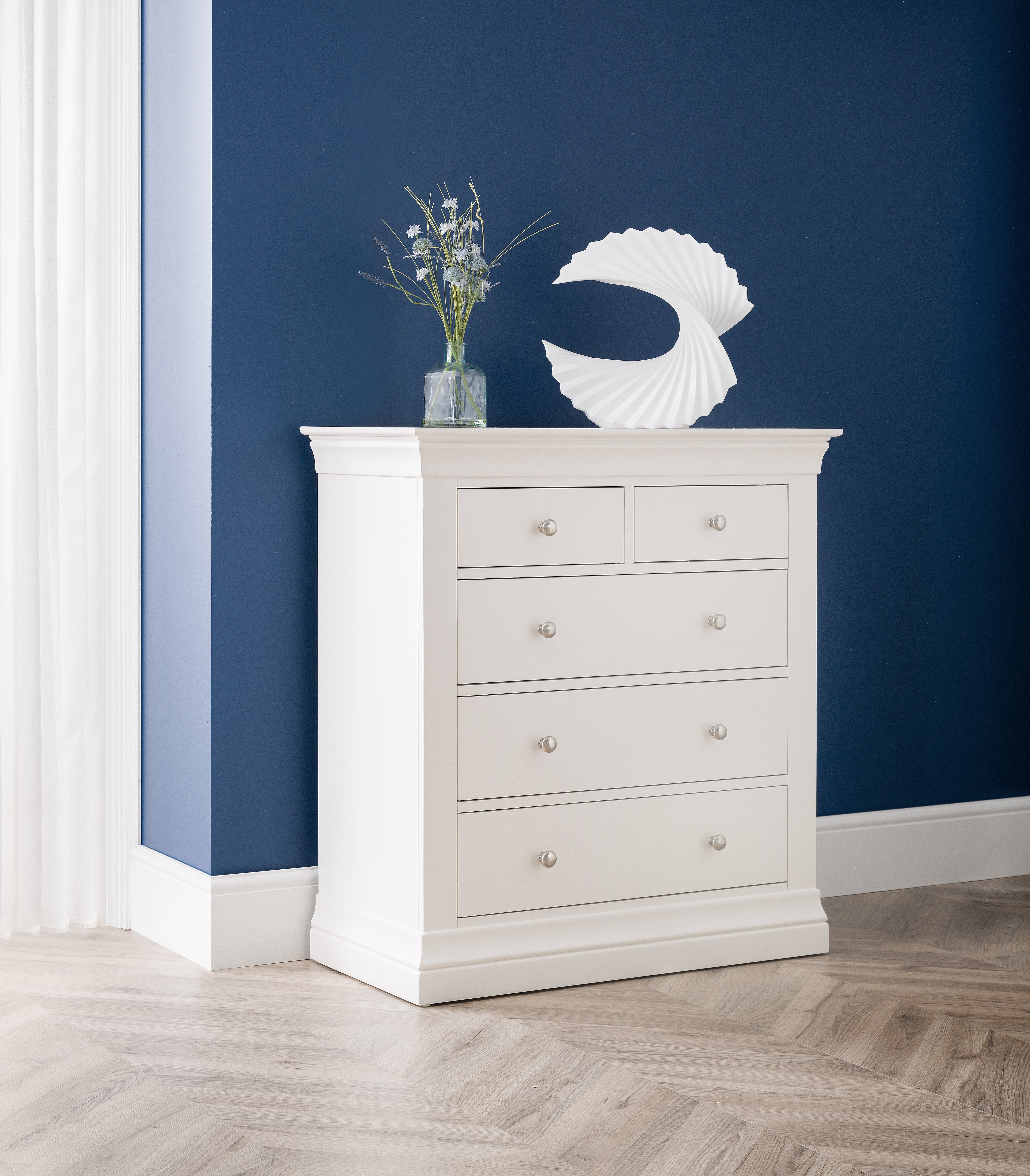 White dresser with decorative items against a blue wall