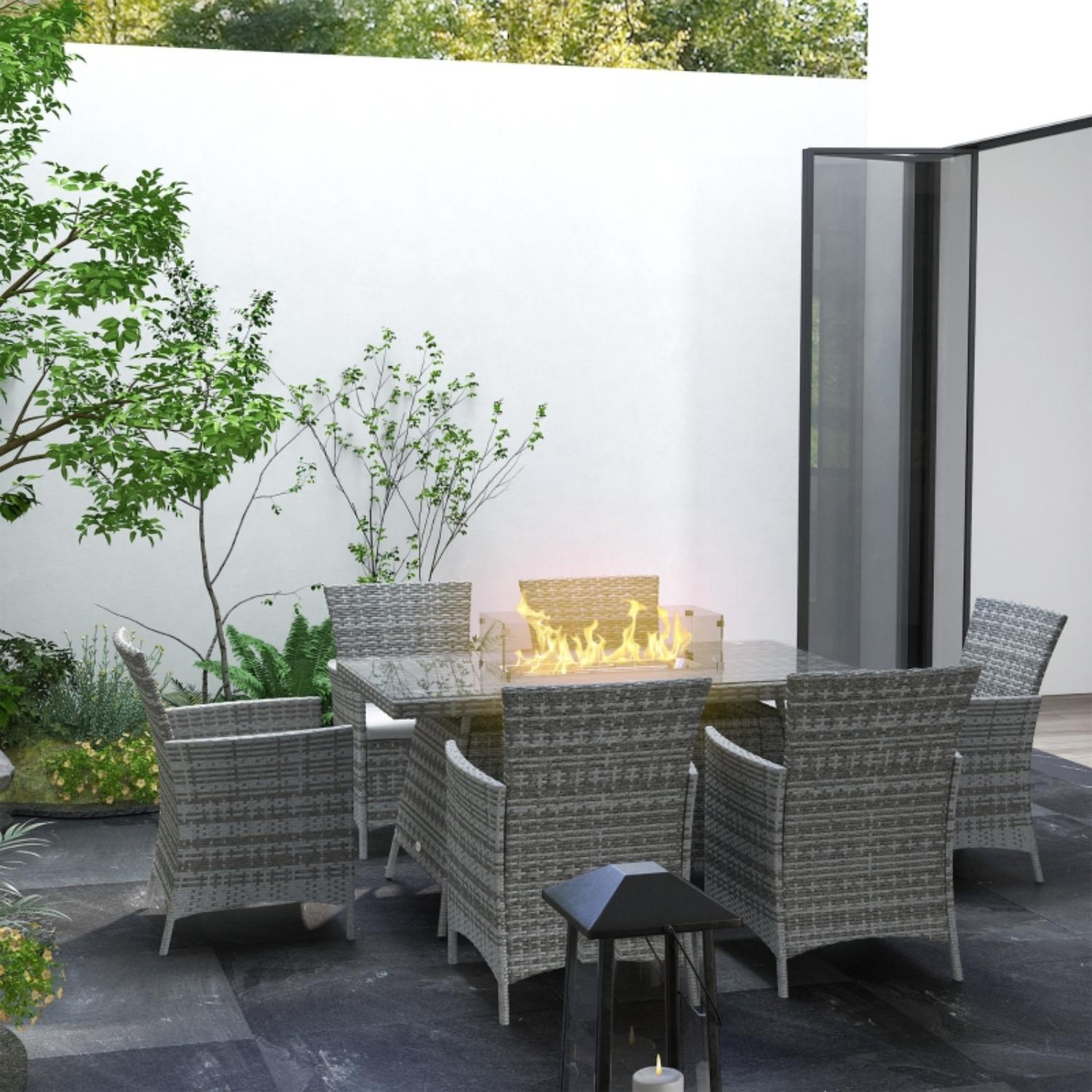 Outdoor patio set with fire pit table and chairs in a garden setting.