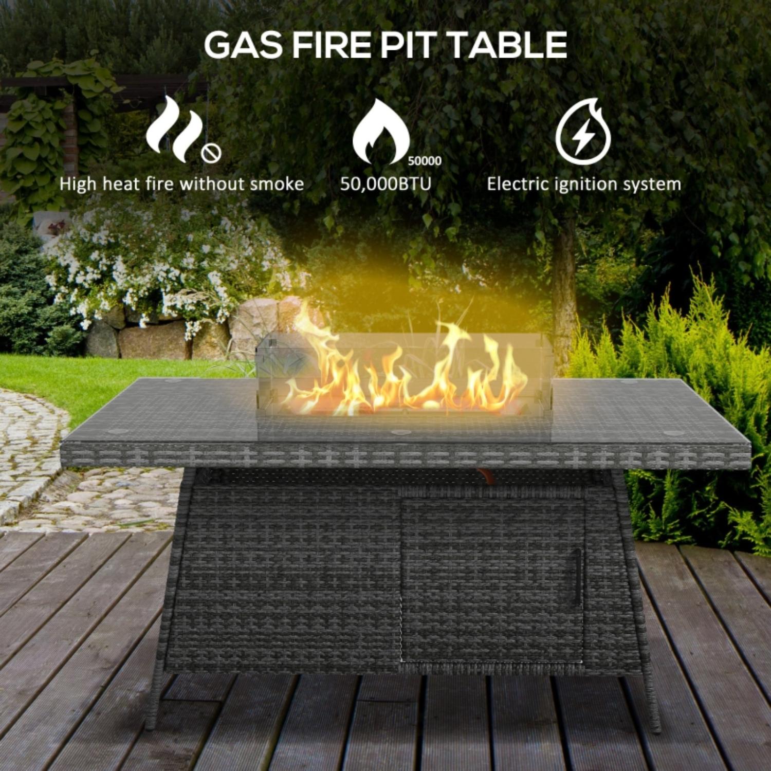 Gas fire pit table with flames on a wooden deck, surrounded by greenery.