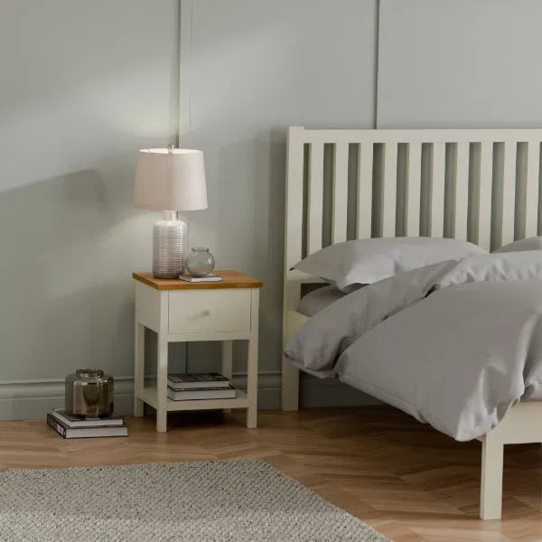 Bedroom with a bed and nightstand featuring a lamp and decor items.