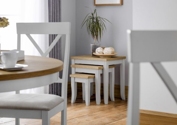 Dining area with wooden table, chairs, and small tables in a room with light gray walls.