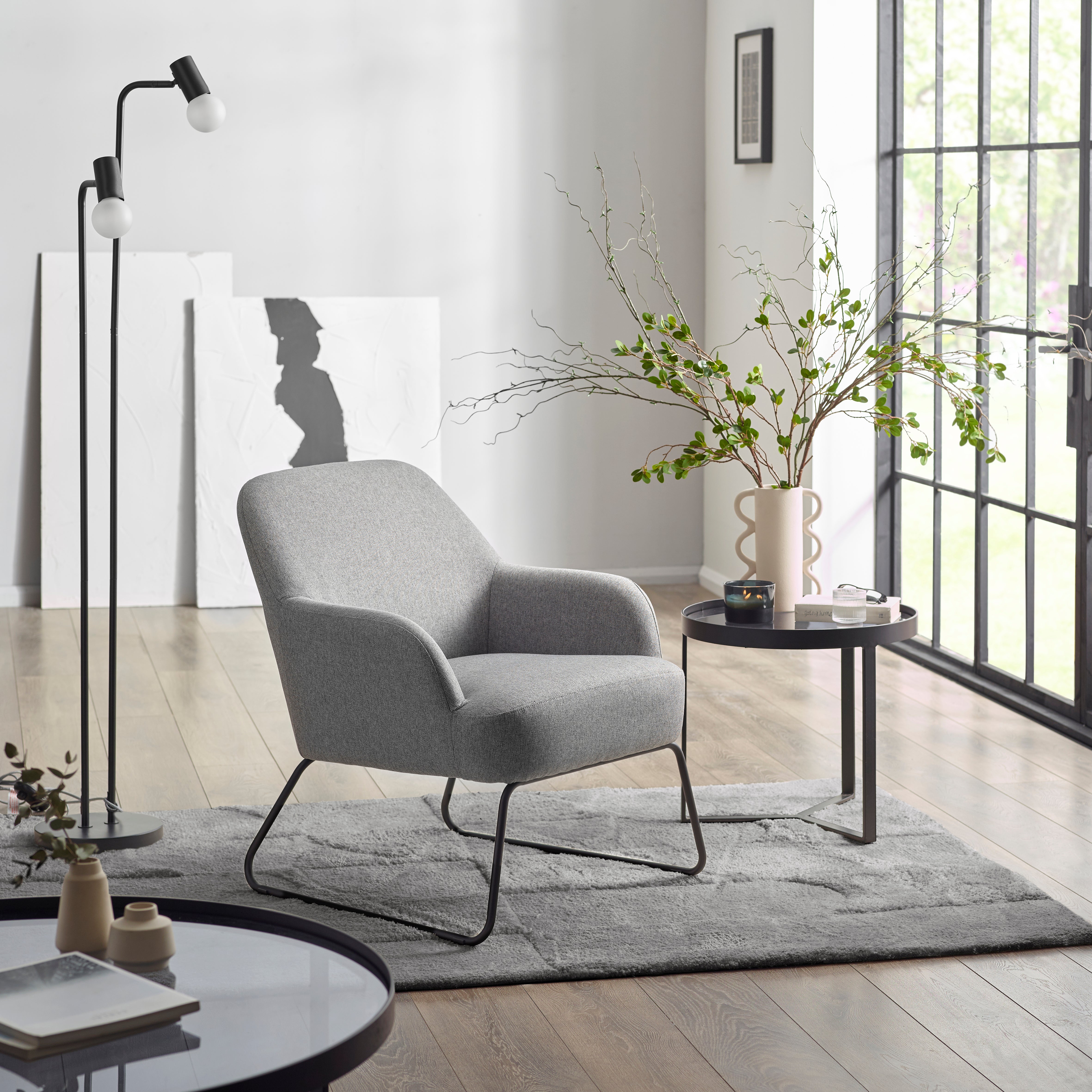 Modern living room with a gray armchair, round coffee table, and floor lamp.