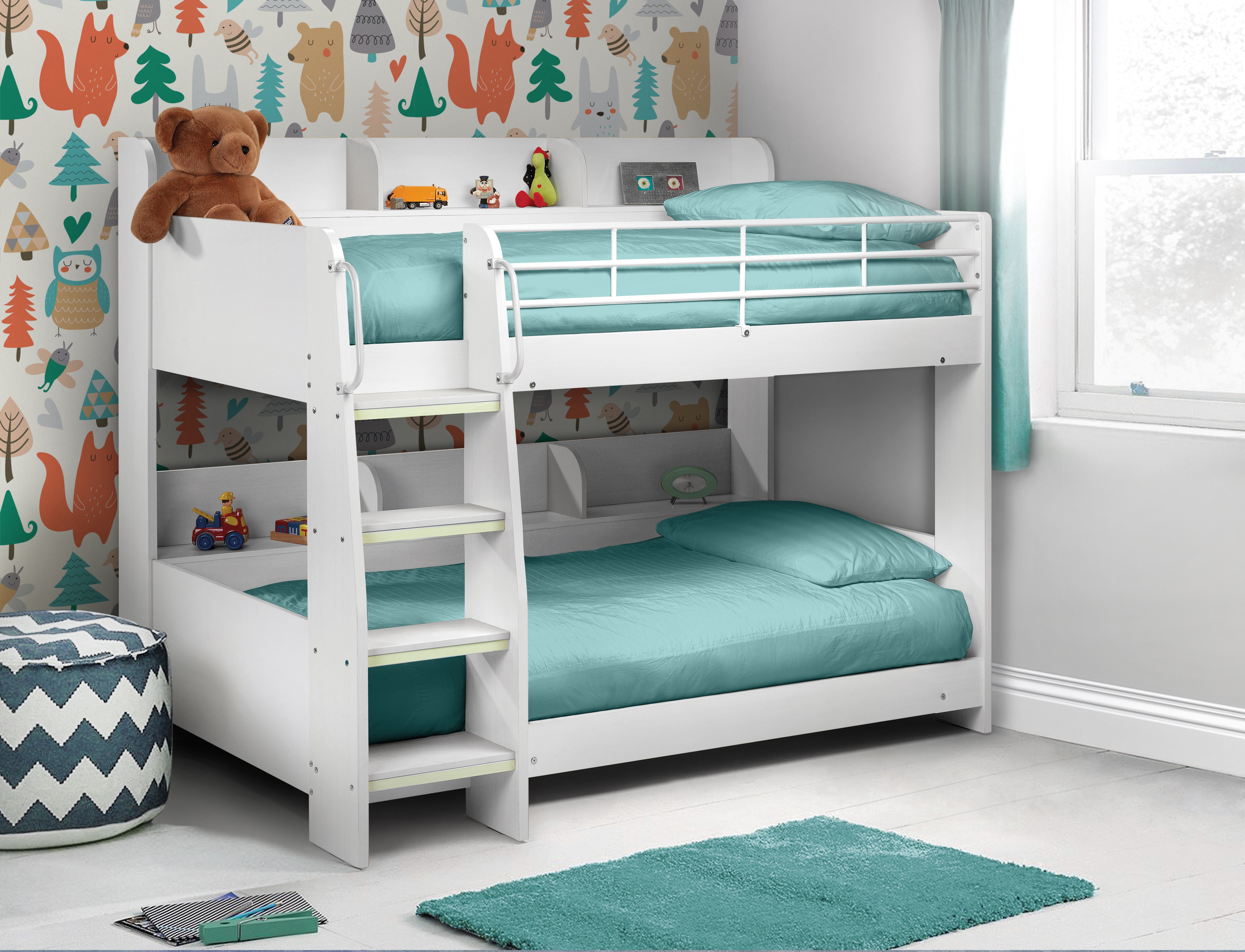 White bunk bed with teal bedding in a child's room with colorful wallpaper and toys.