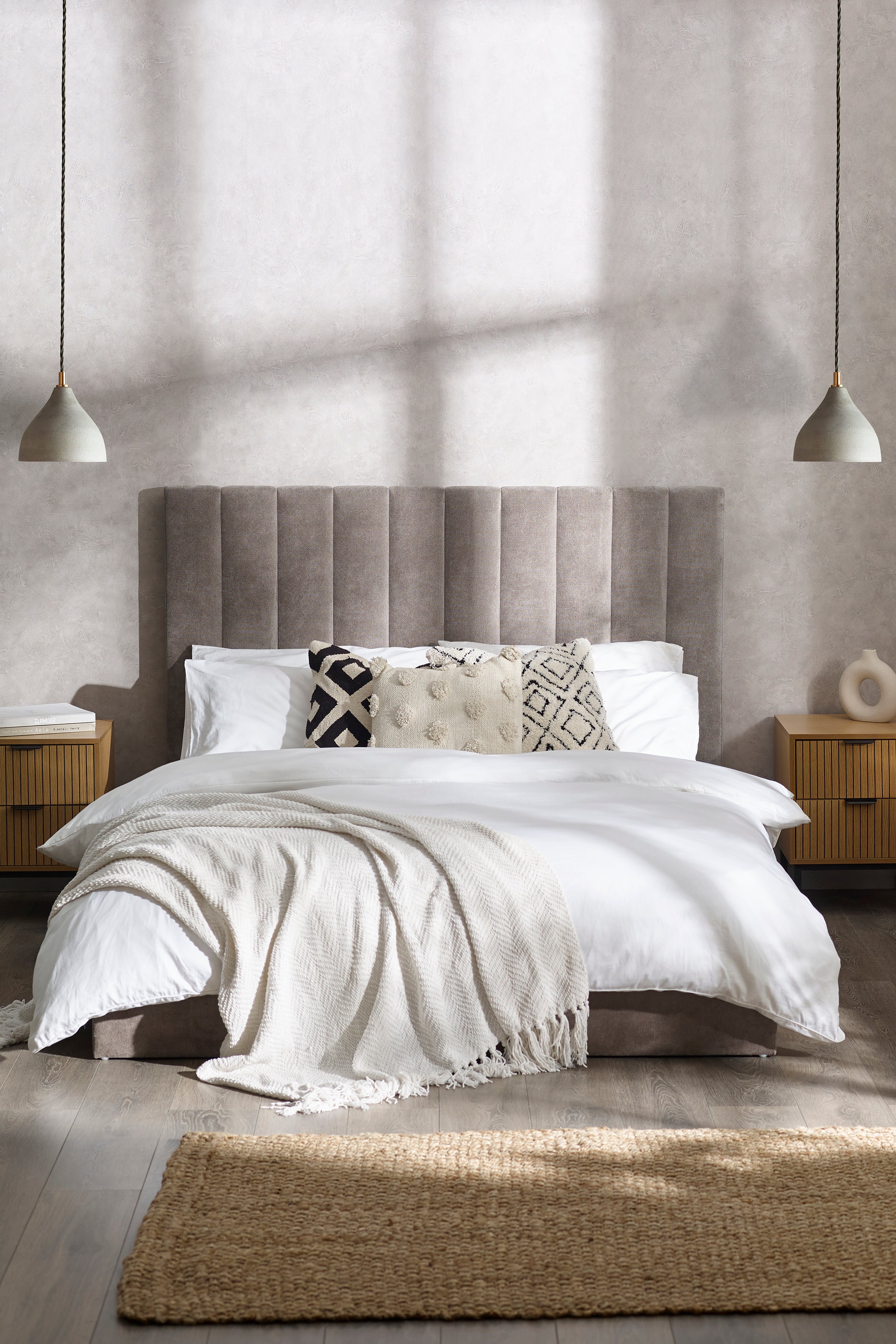 Neatly made bed with white bedding and decorative pillows in a bedroom setting.