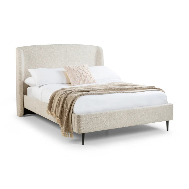 Beige upholstered bed with white bedding and a beige blanket on a white background