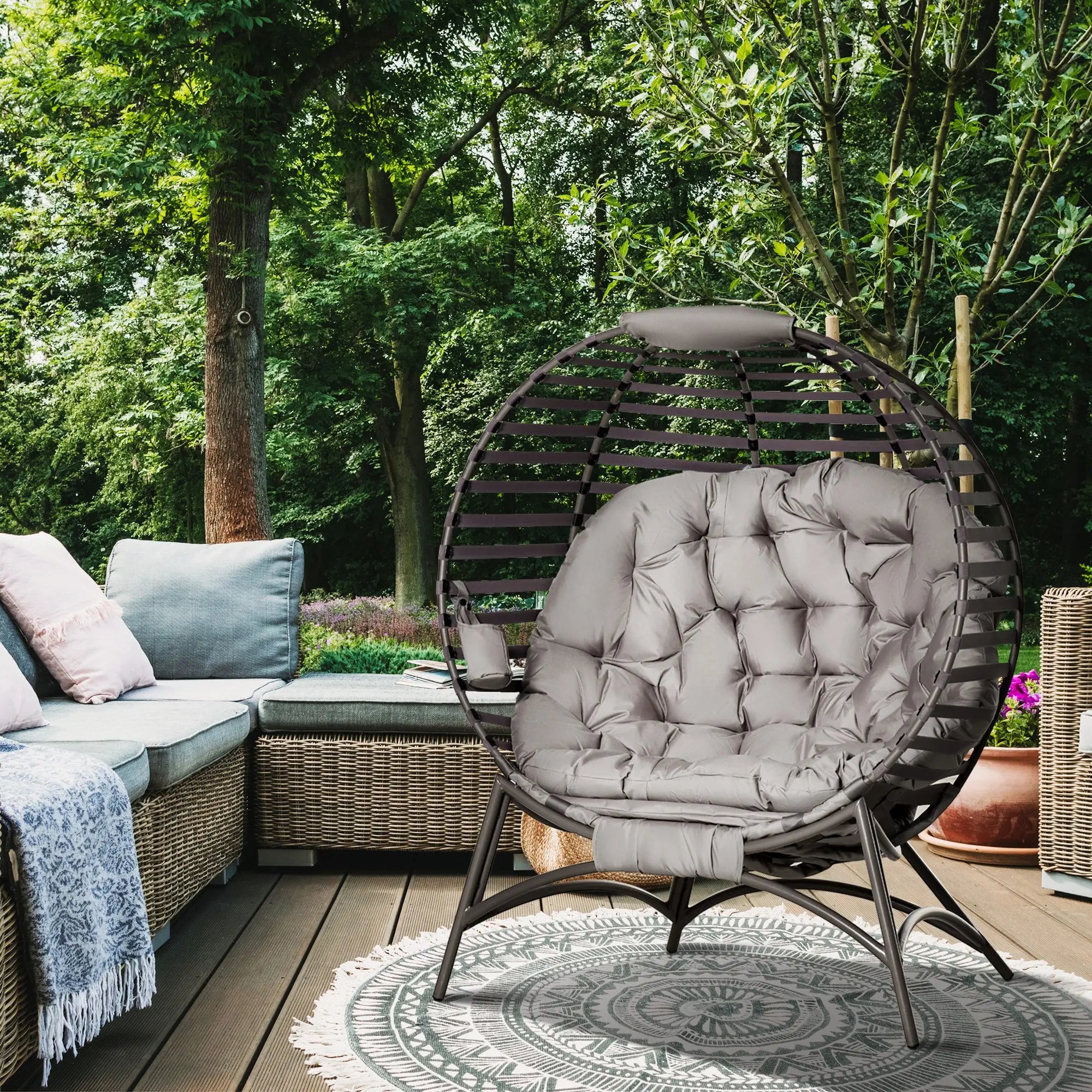 Outdoor patio setting with a wicker egg chair and sectional sofa in a garden.