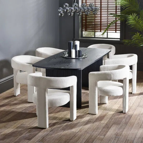 Dining room with a black table and white chairs on a wooden floor.