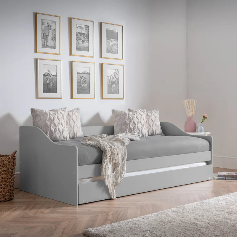 Gray daybed with pillows and a blanket in a room with framed pictures on the wall.