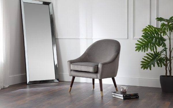 Gray armchair in a room with a large mirror and a plant.