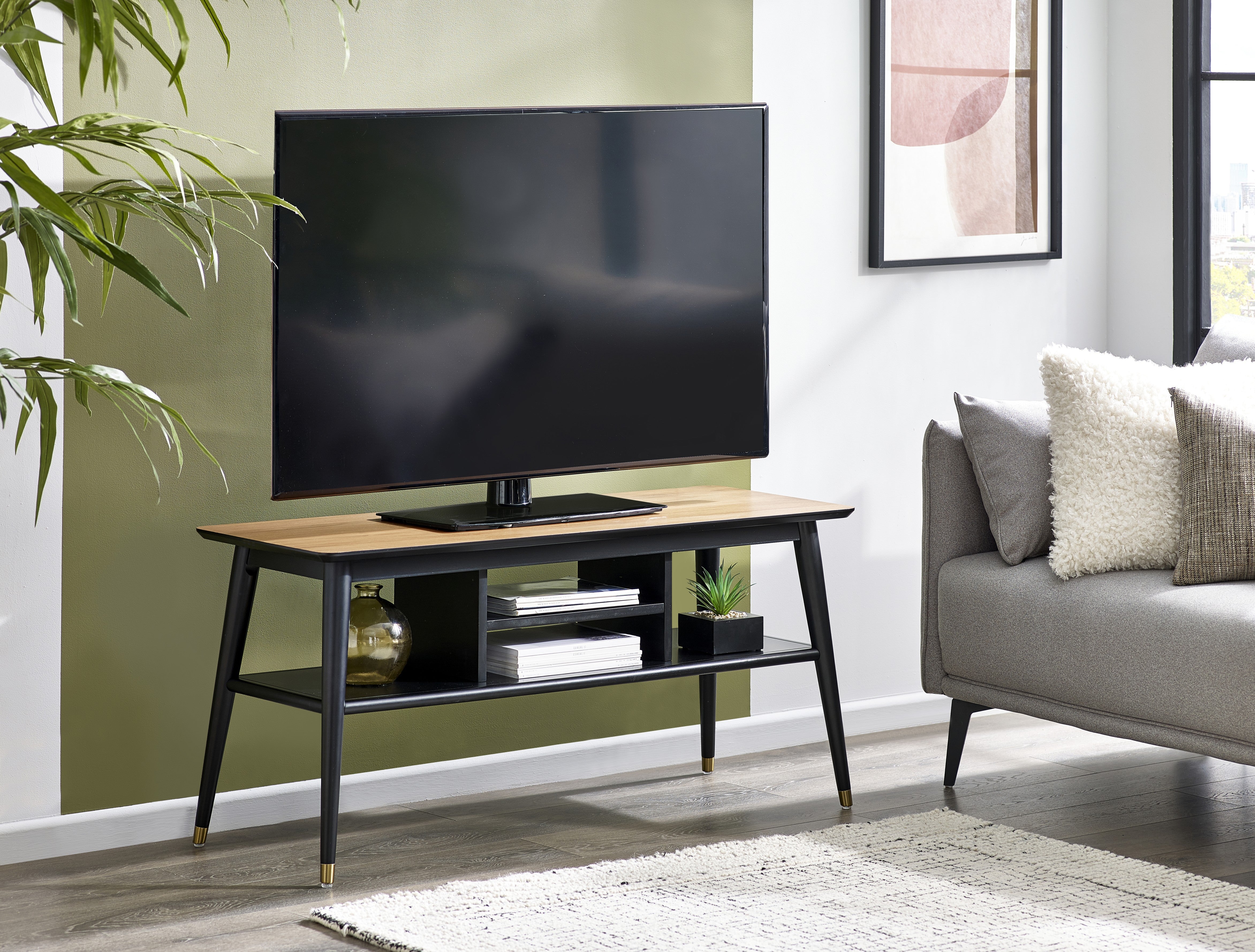 Modern living room with a TV on a wooden stand, gray sofa, and decorative elements.