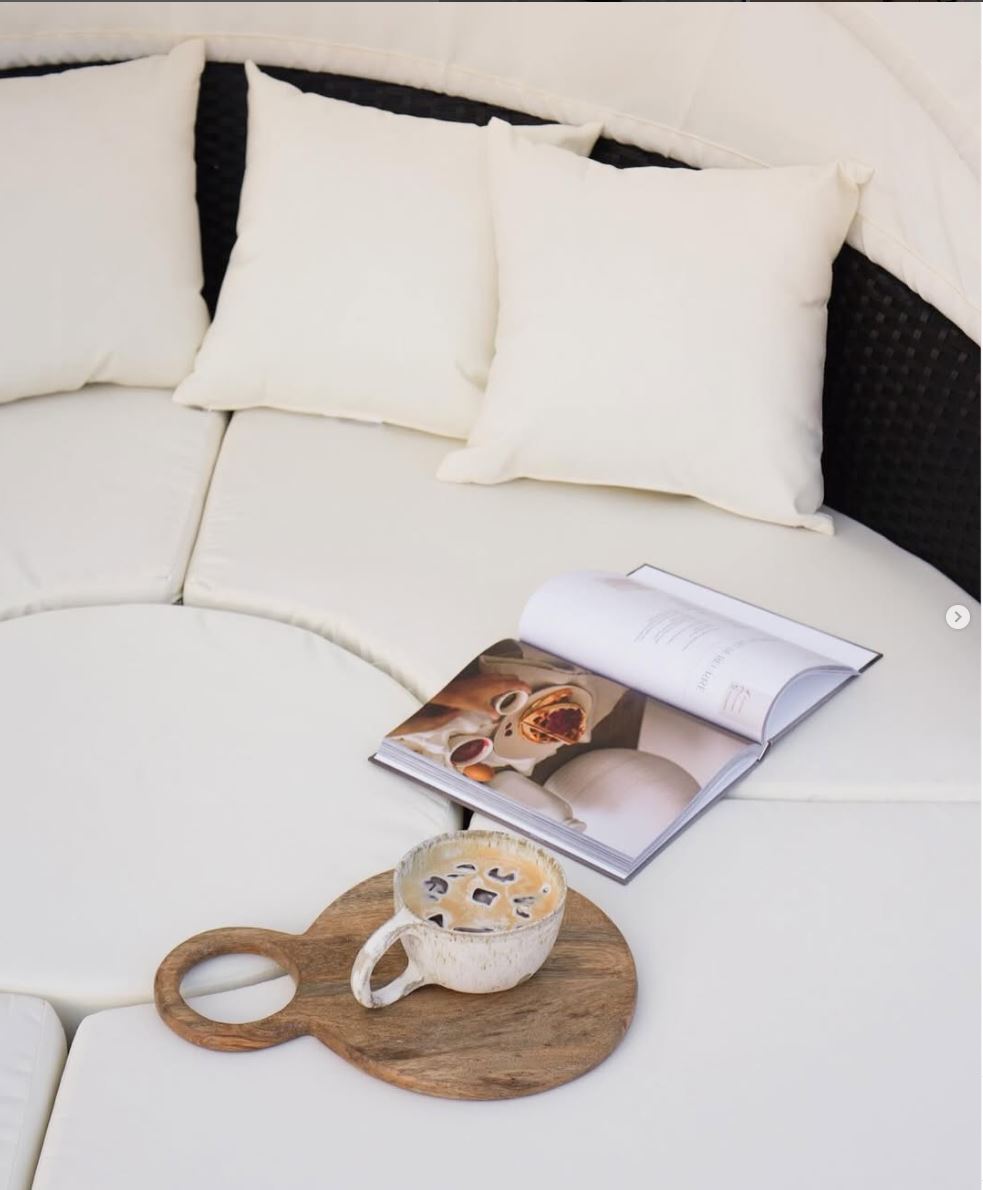 White sofa with a wooden tray holding a cup and a magazine on a white surface