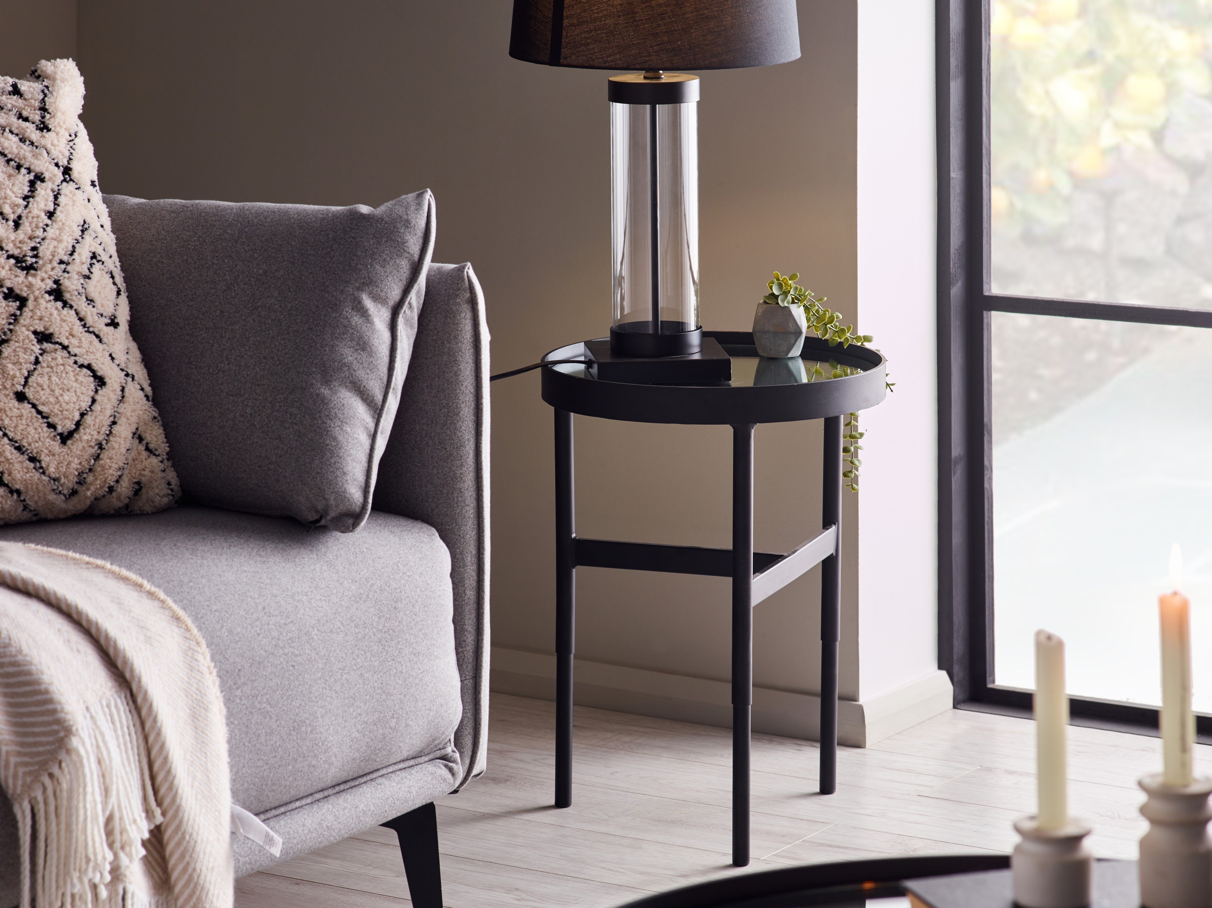 Gray armchair with decorative pillows and a side table in a living room setting.