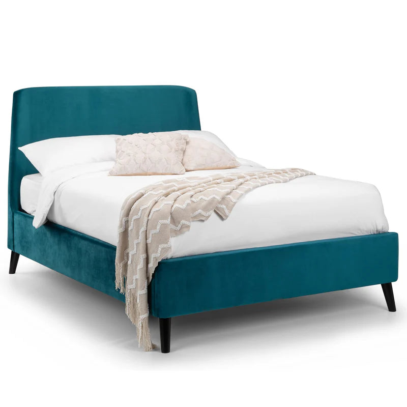 Teal bed with white bedding and beige blanket on a white background