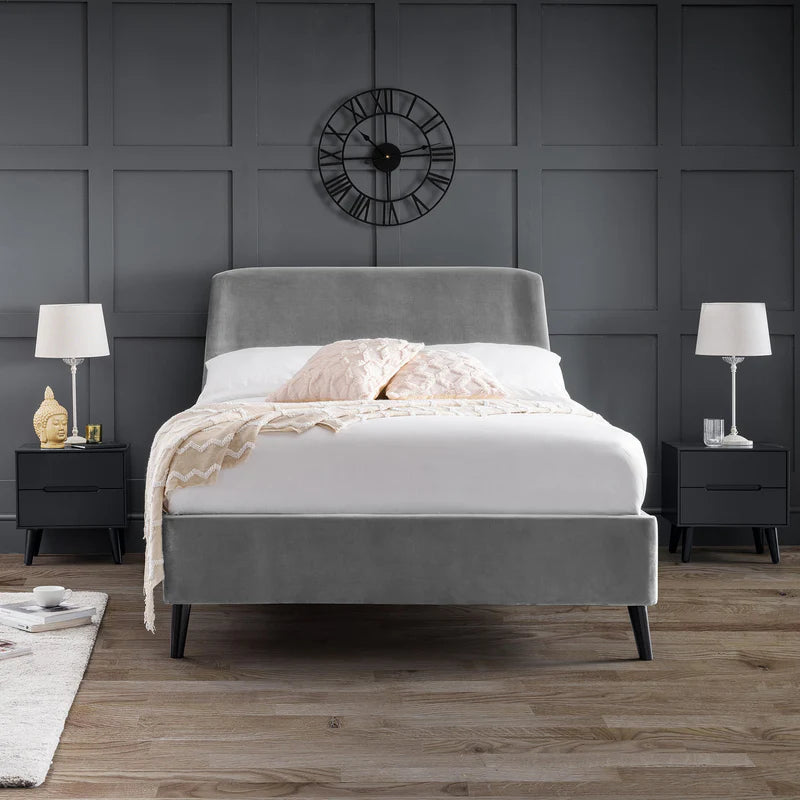 Gray upholstered bed with white bedding in a bedroom setting.