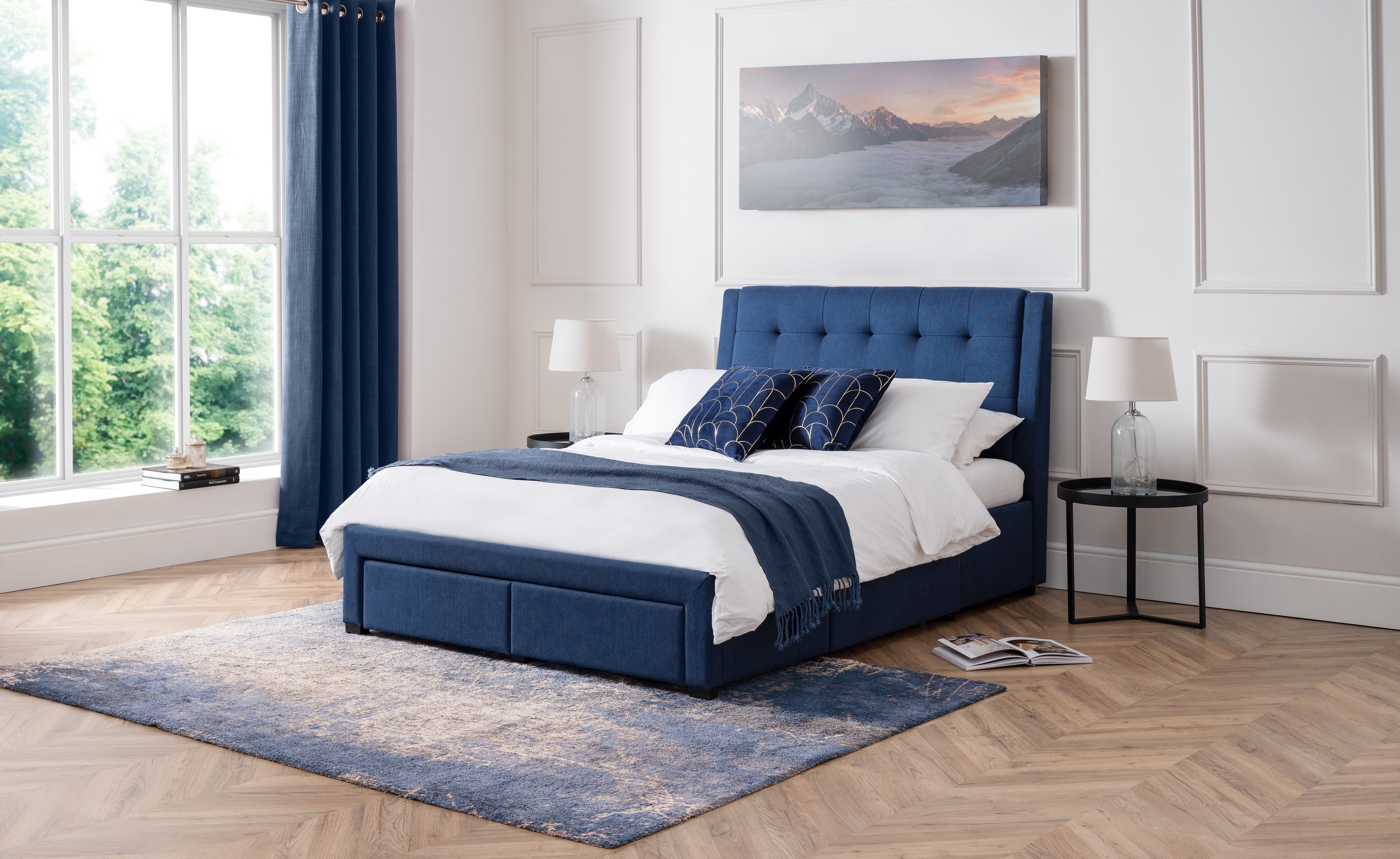 Modern bedroom with a blue upholstered bed, white bedding, and decorative pillows.