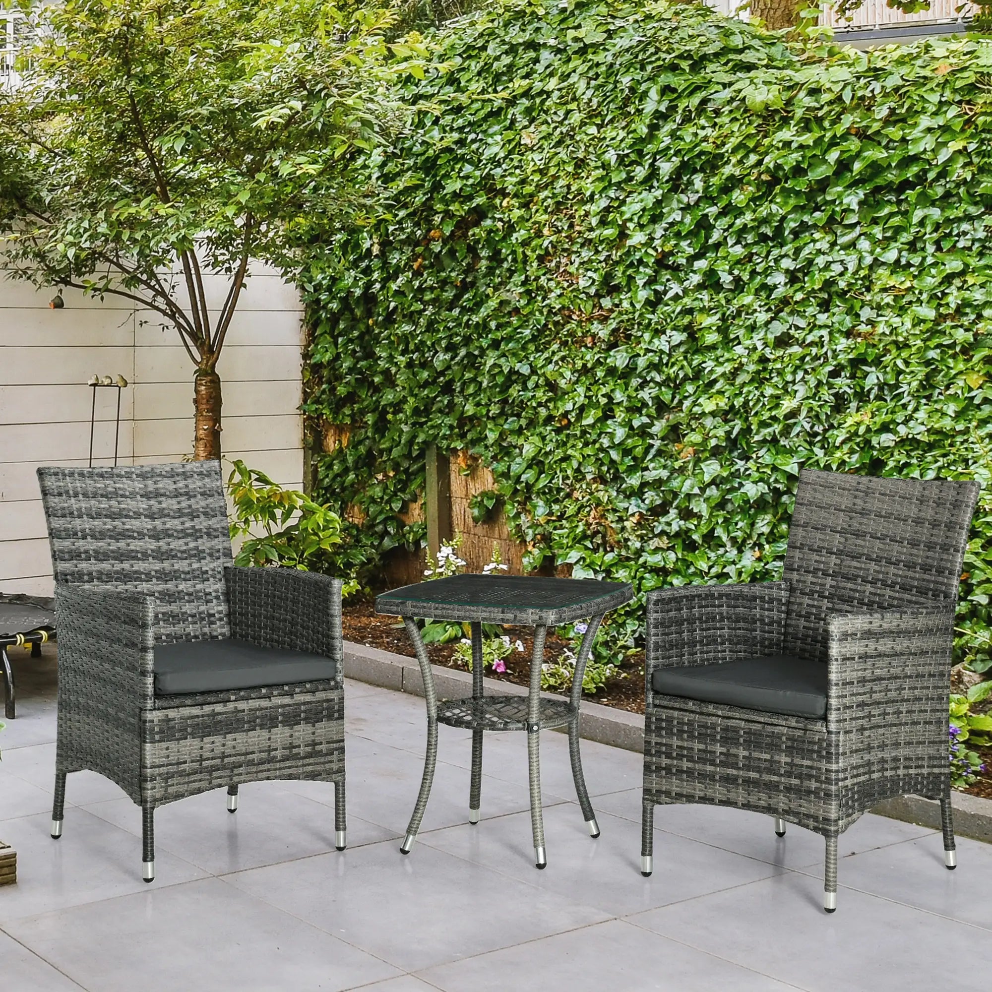 Two gray wicker chairs with black cushions and a matching table on a patio.