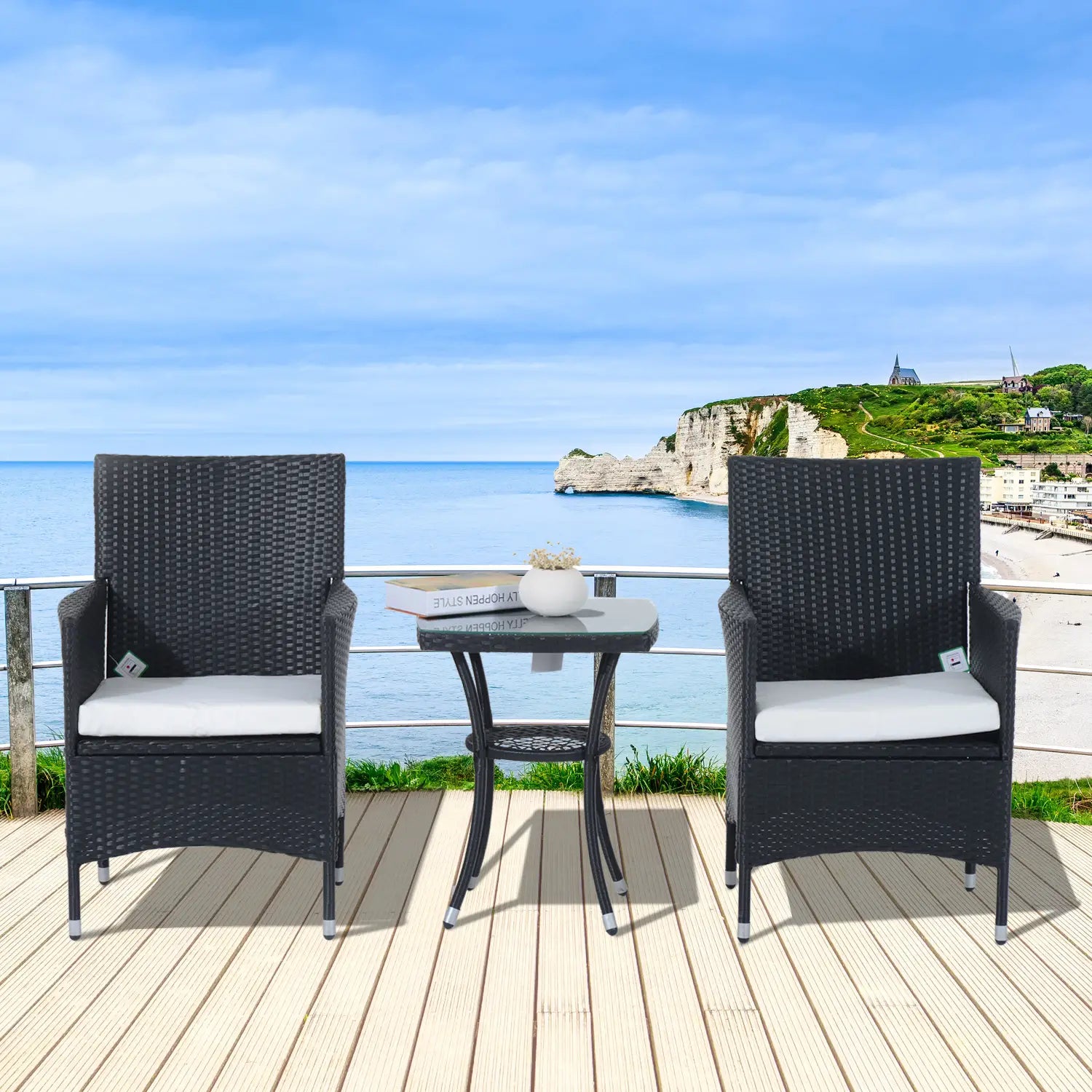 Outdoor patio set with two chairs and a table on a deck overlooking the ocean.