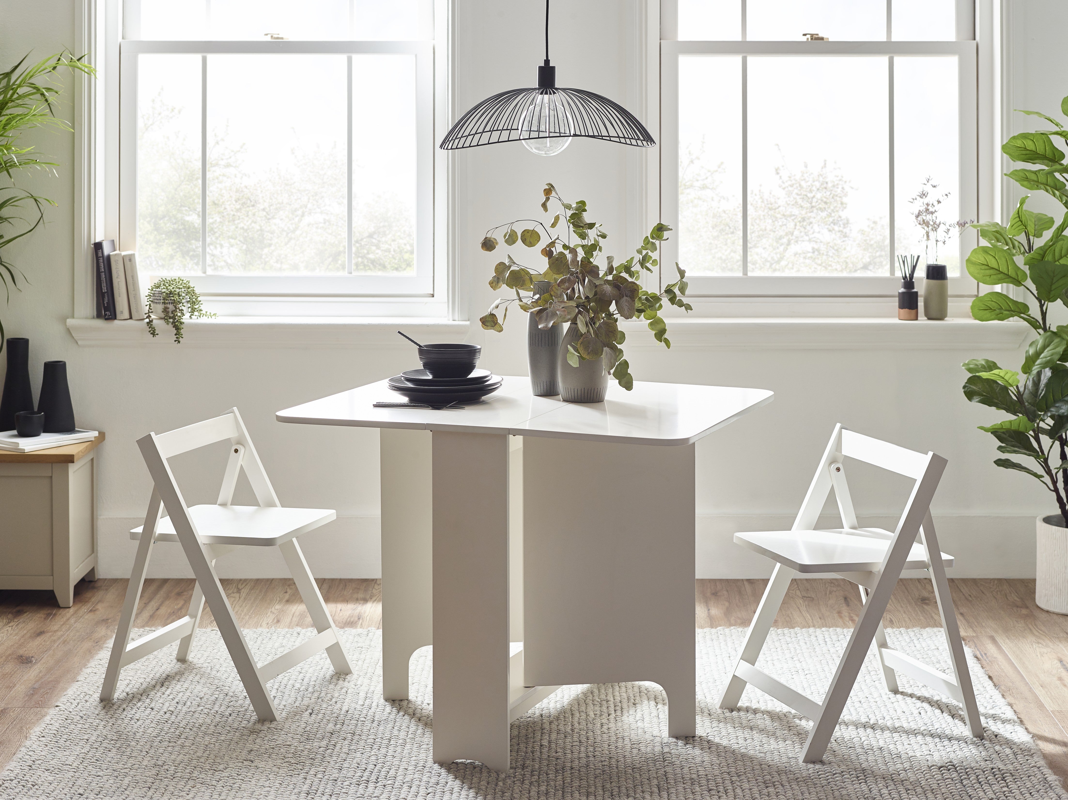 Modern dining area with a white table and chairs in a bright room.