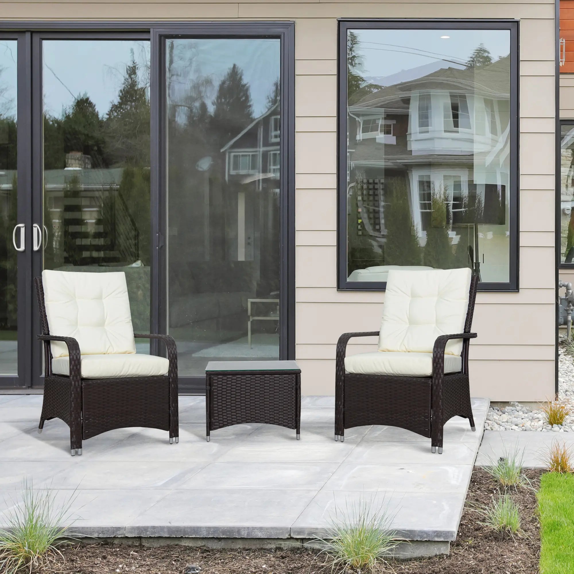 Two wicker chairs with white cushions and a matching table on a patio.