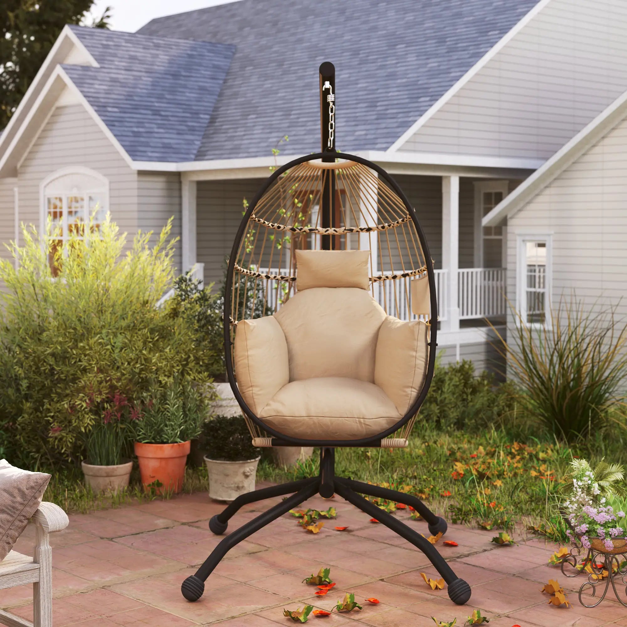 Beige egg-shaped hanging chair on a patio with a house in the background