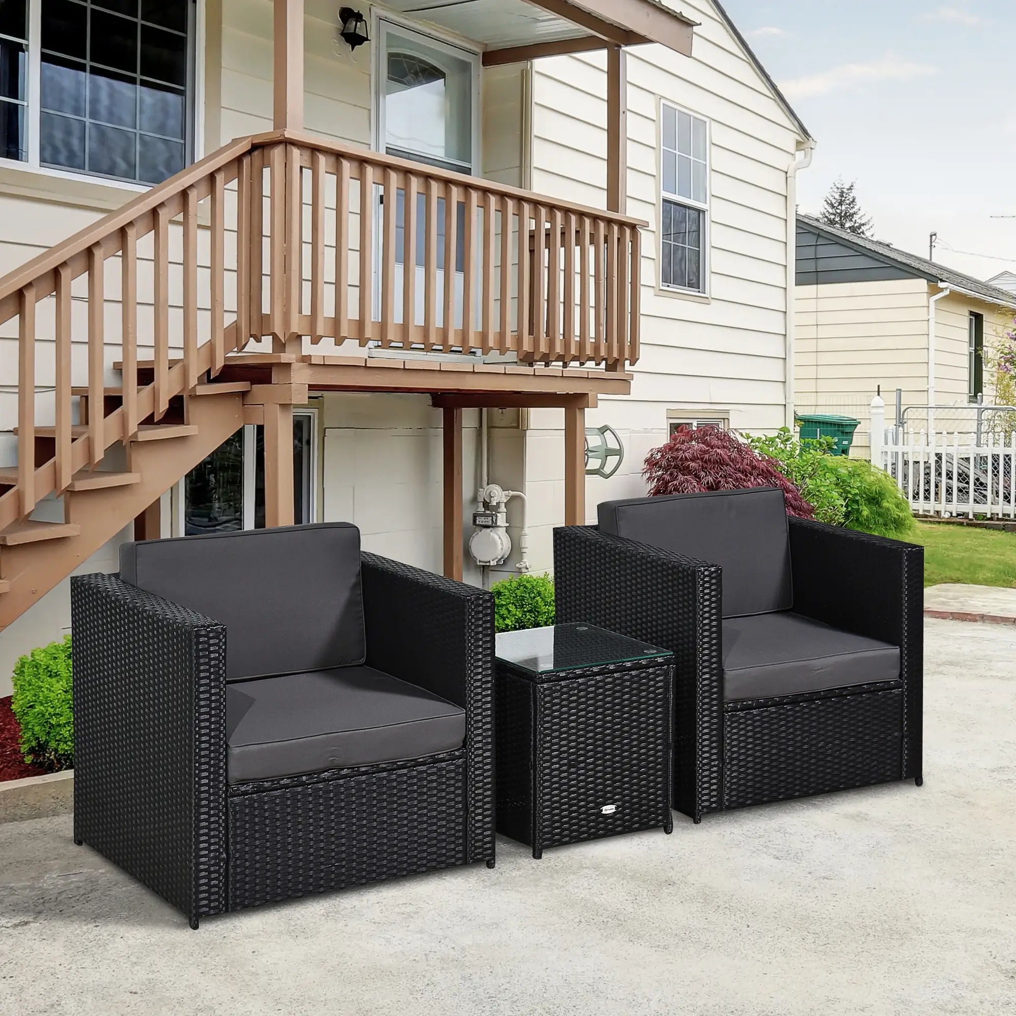 Black outdoor furniture set with gray cushions on a patio in front of a house.