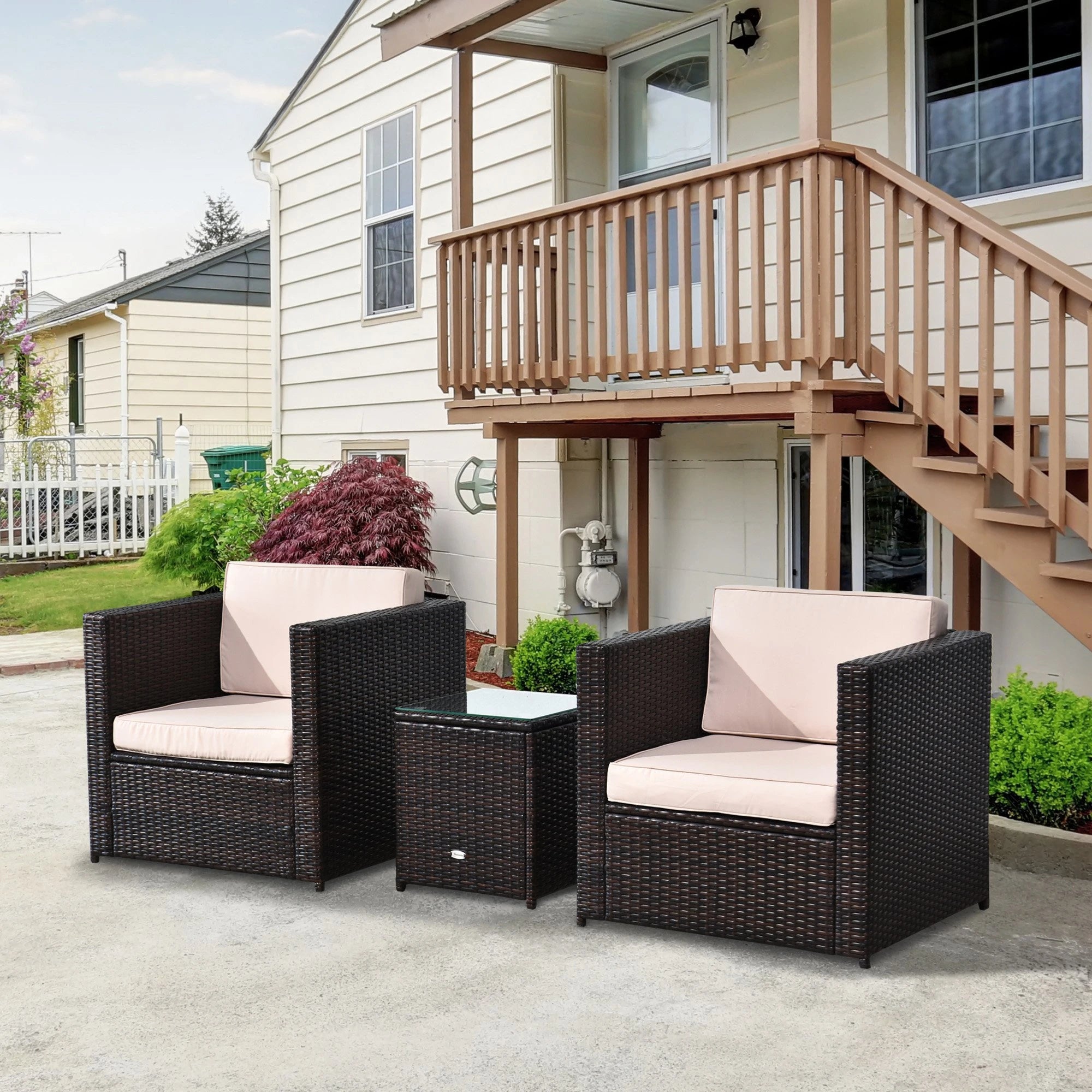 Wicker outdoor furniture set with pink cushions in front of a house.