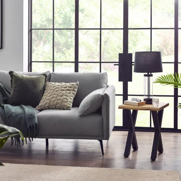 Gray sofa with decorative pillows in a modern living room with large windows.