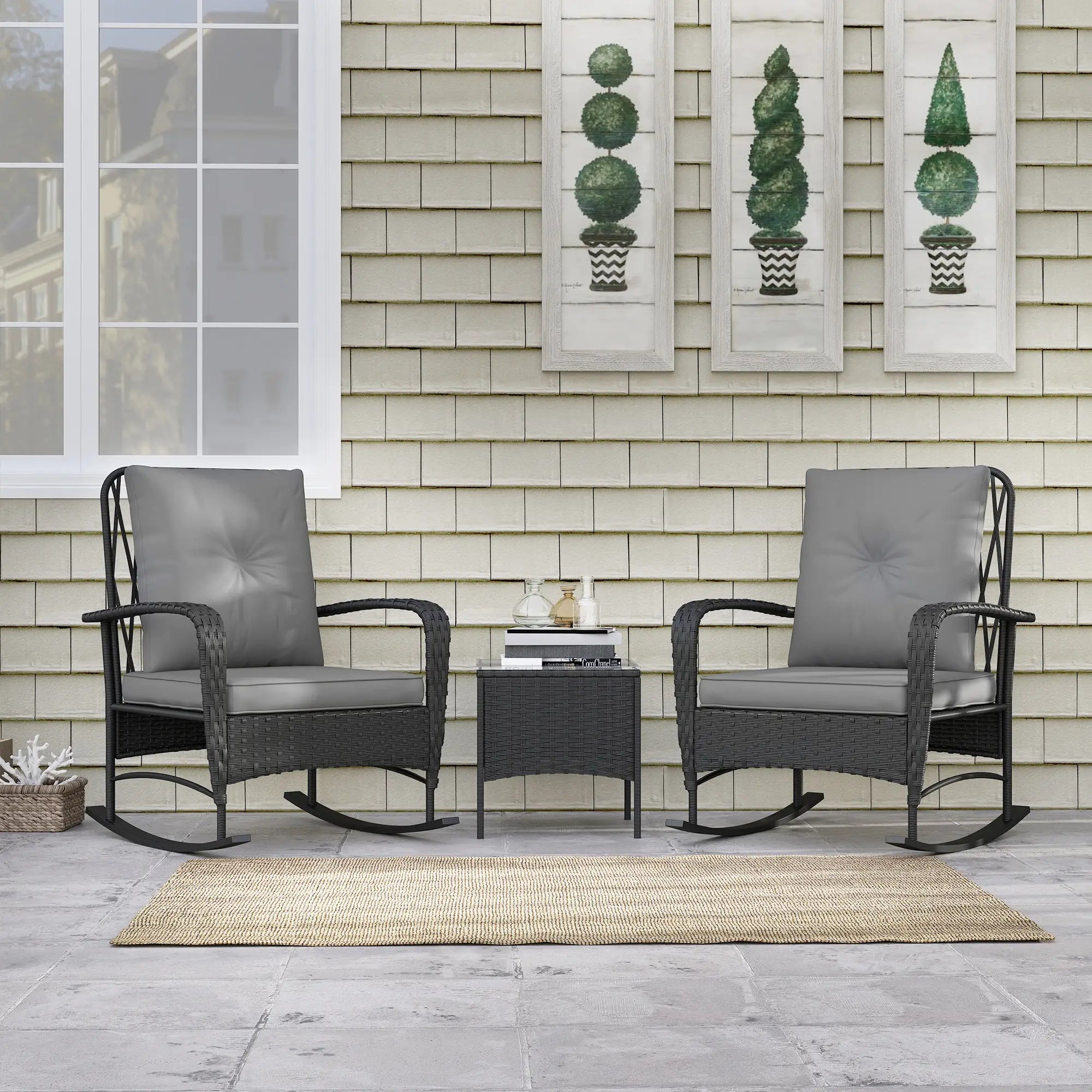 Two black rocking chairs with gray cushions on a patio with a small table.
