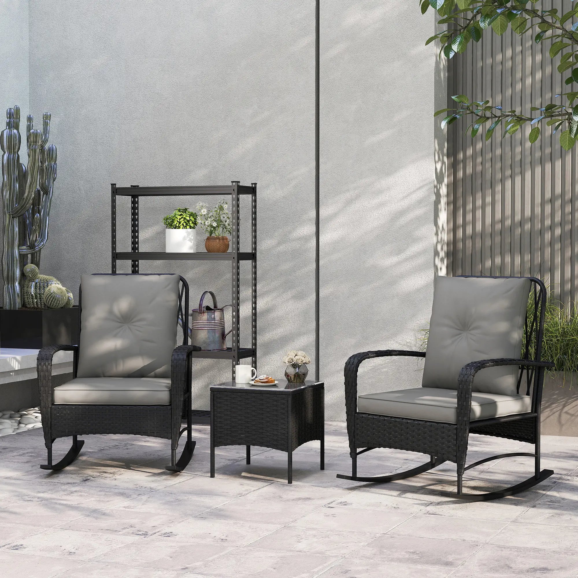 Outdoor patio set with two rocking chairs and a small table on a stone patio.
