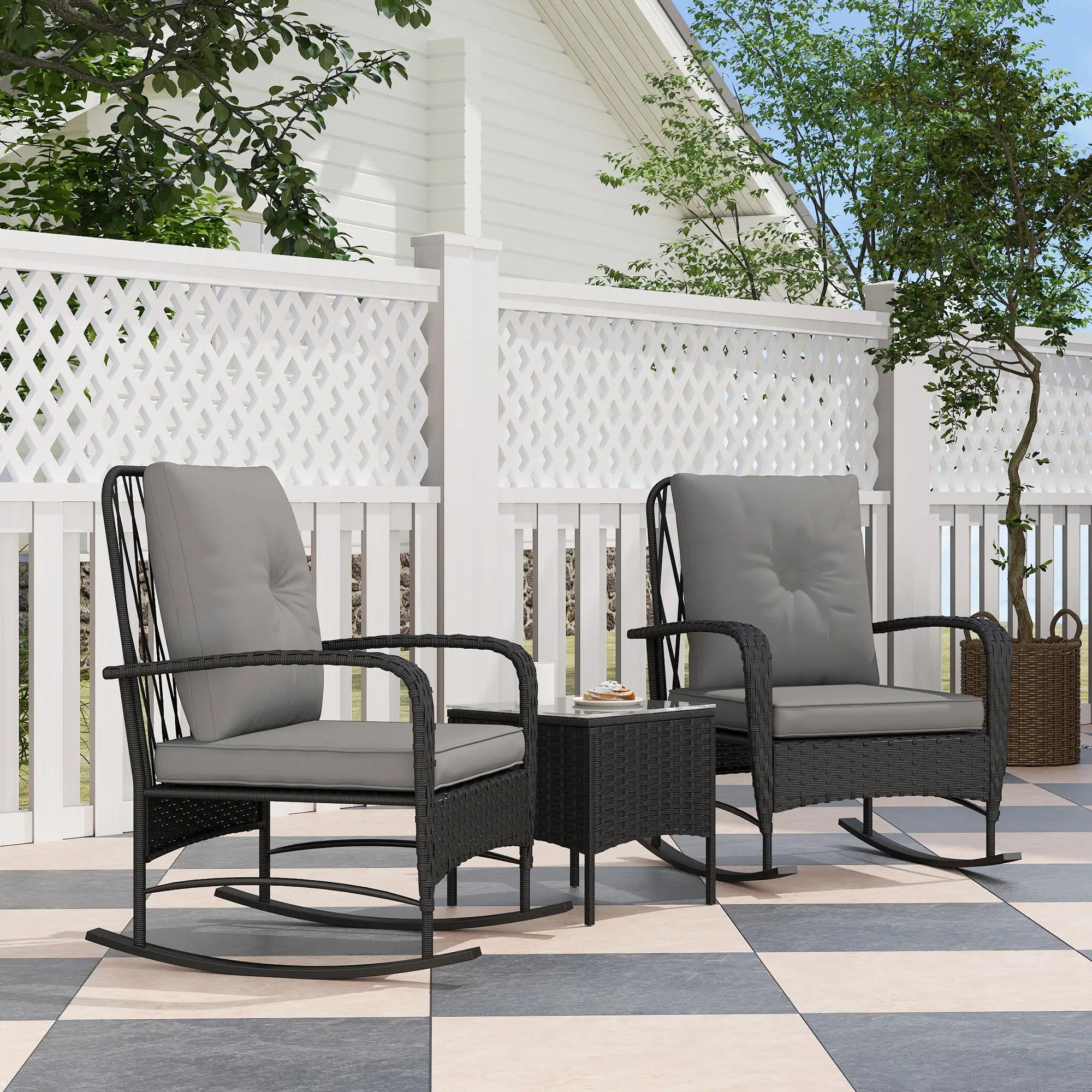Two gray cushioned rocking chairs with a small table on a patio.