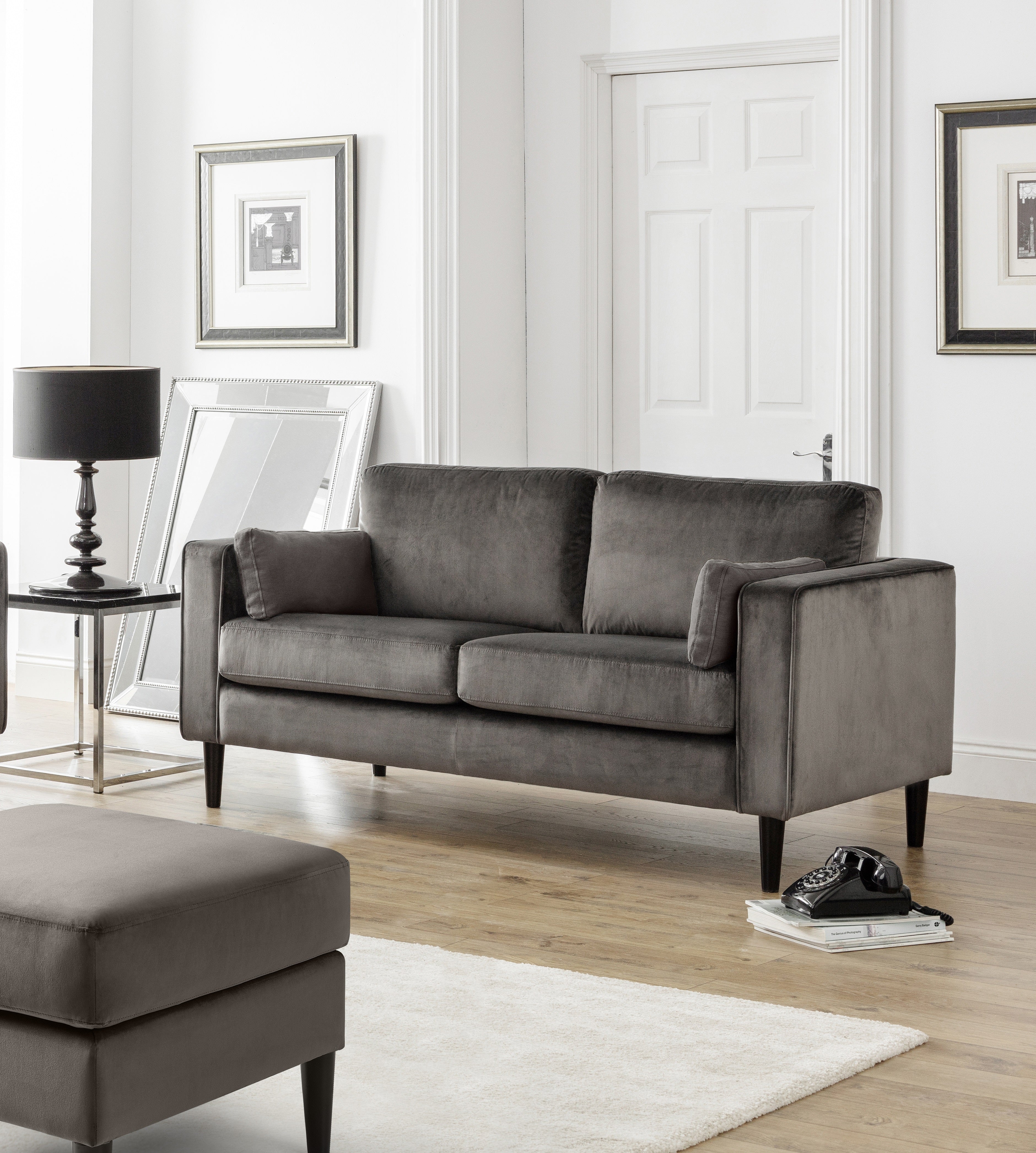 Gray sofa in a living room with a lamp, table, and rug.