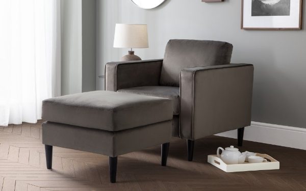 Gray chaise lounge chair in a room with a lamp and tray on a wooden floor.
