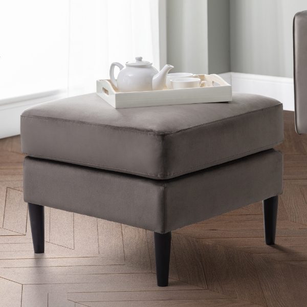 Gray ottoman with a white tray and teapot on a wooden floor.