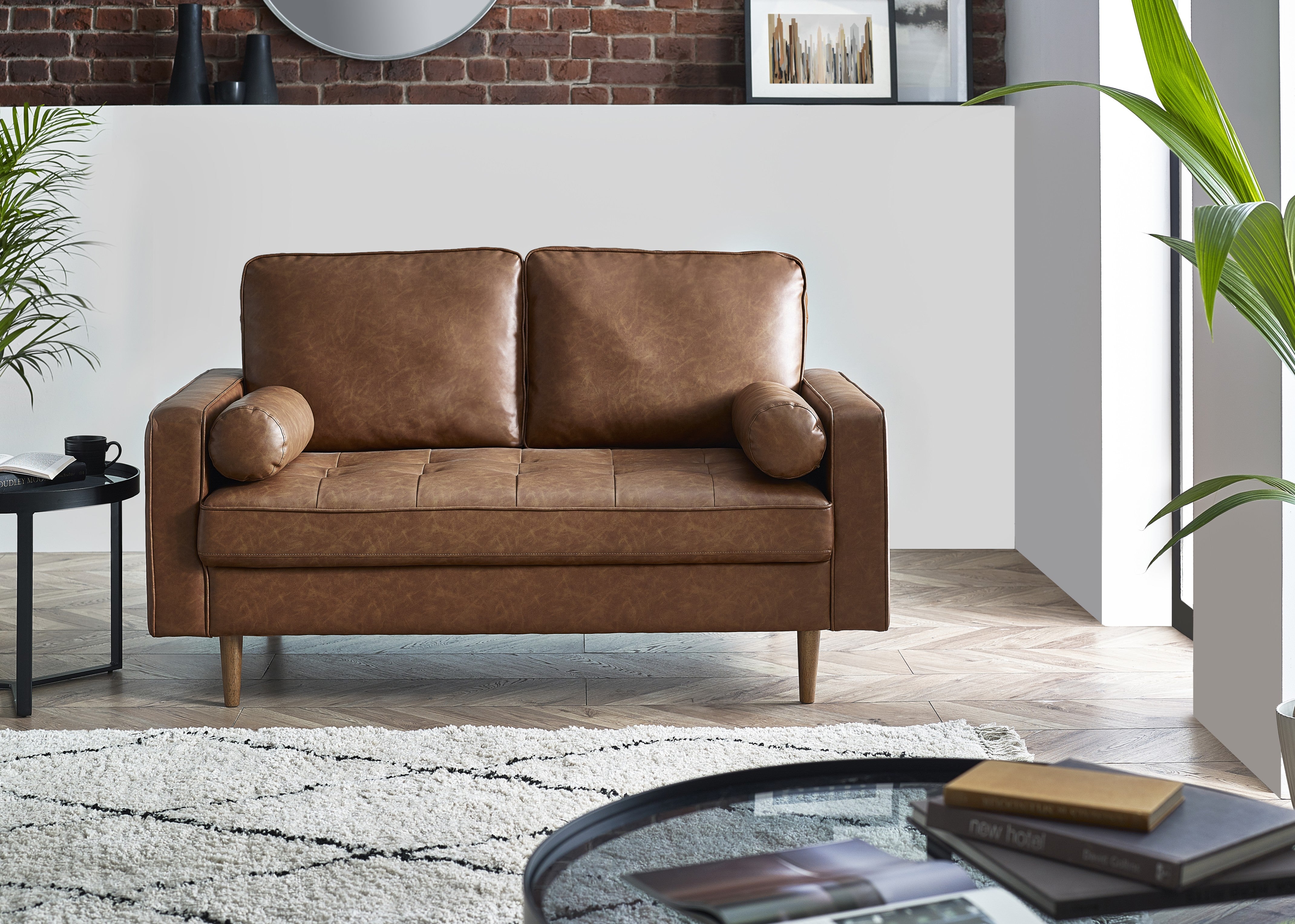 Brown leather sofa in a modern living room with plants and a coffee table.