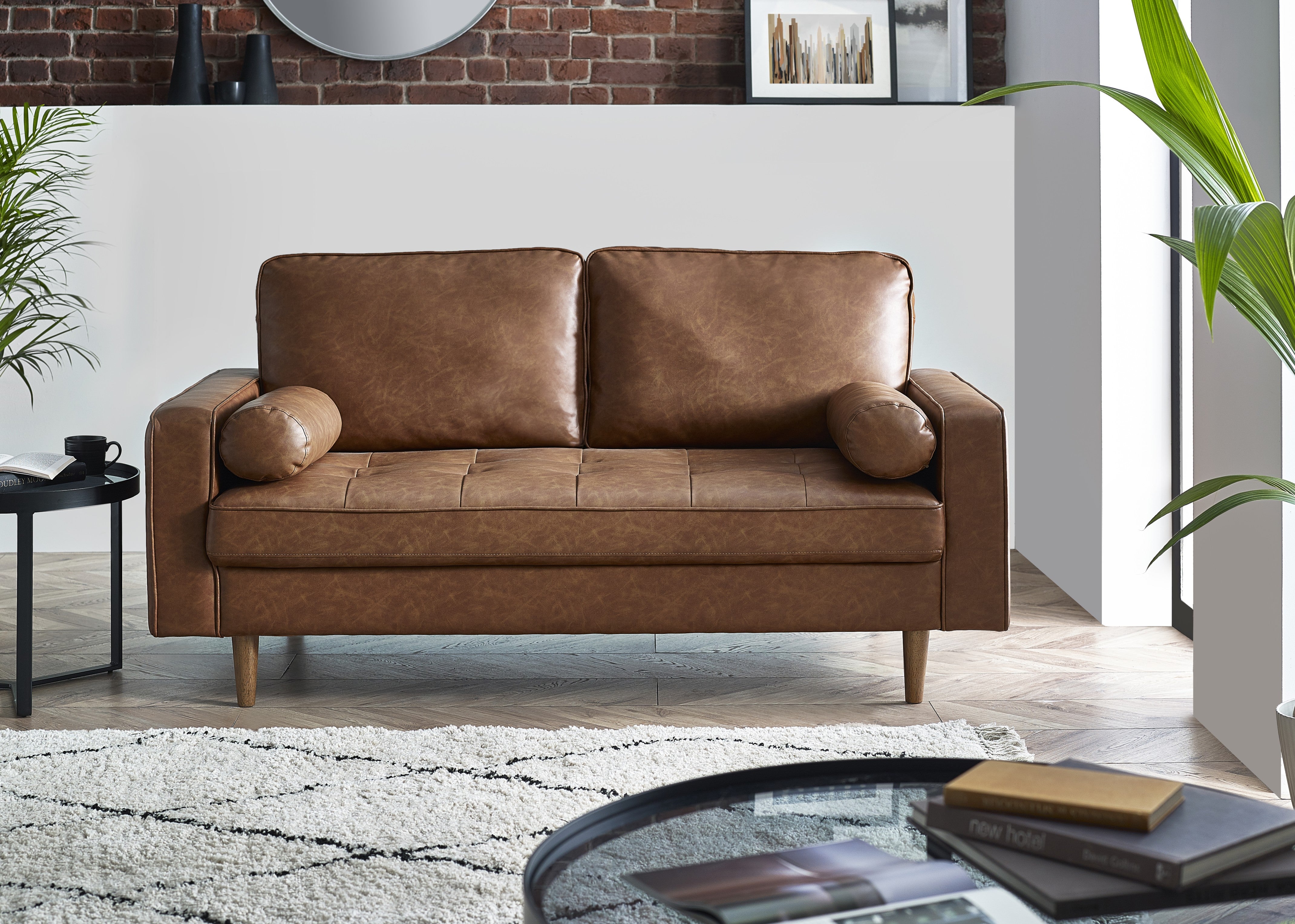 Brown leather sofa in a living room setting with a coffee table and plants.