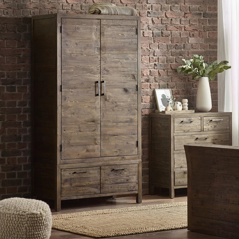 Wooden wardrobe and dresser against a brick wall in a room setting.