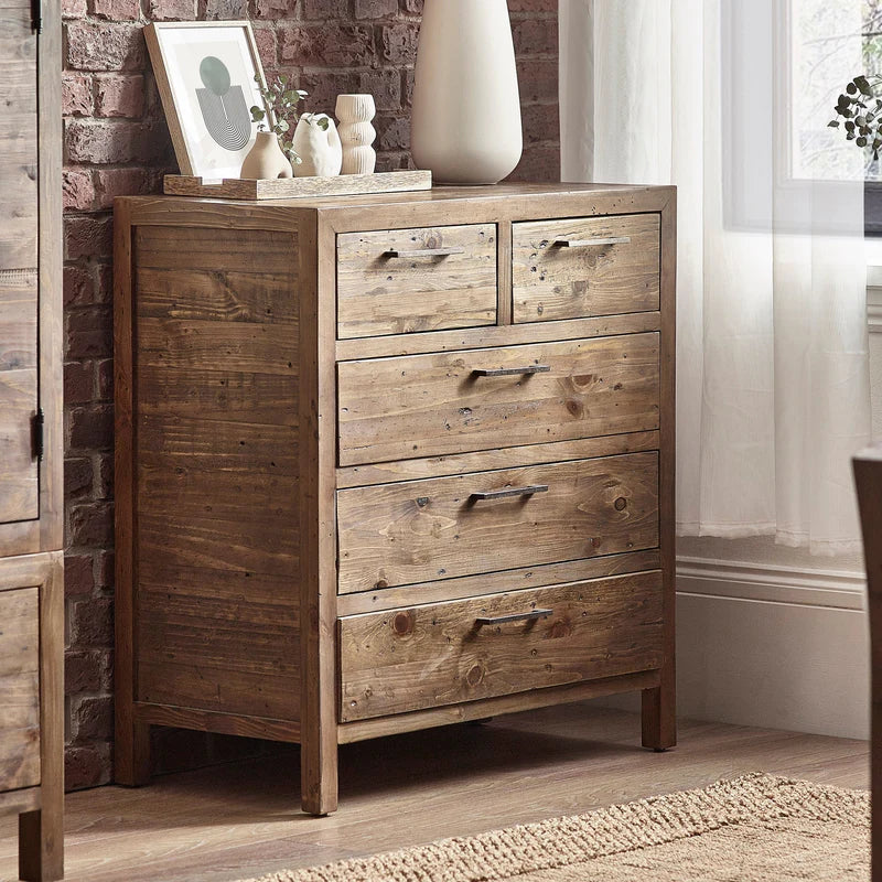 Wooden dresser with four drawers against a brick wall in a room with a rug and window.
