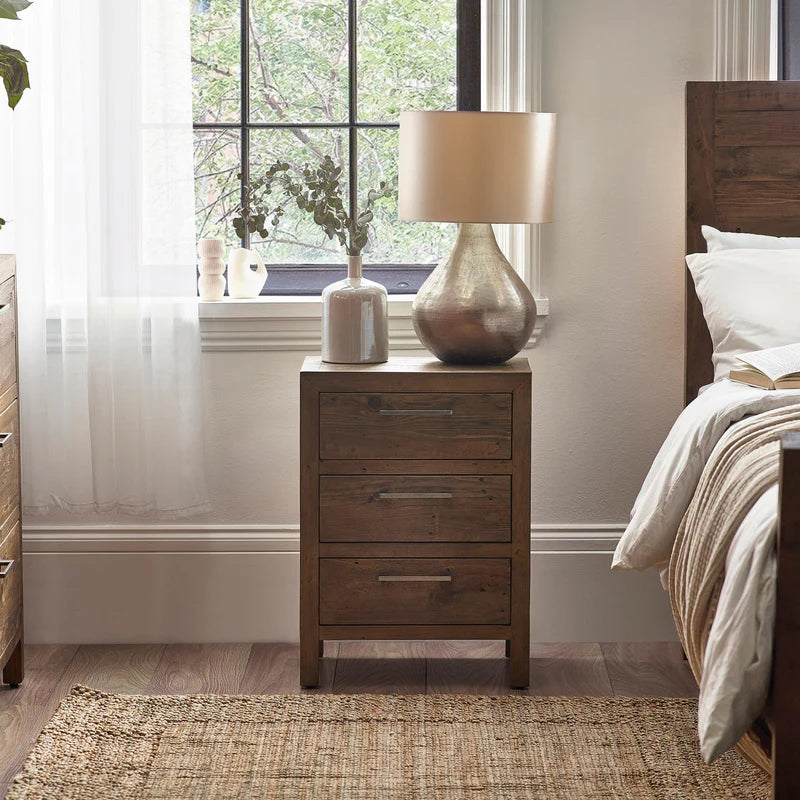 Wooden nightstand with lamp and decor in a bedroom setting