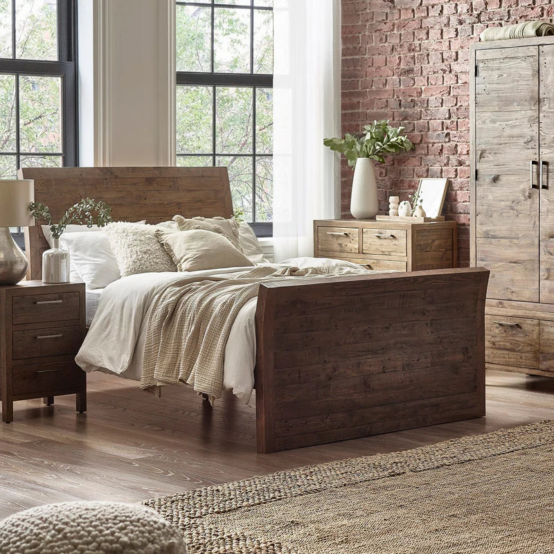 Bedroom with wooden bed and furniture against a brick wall